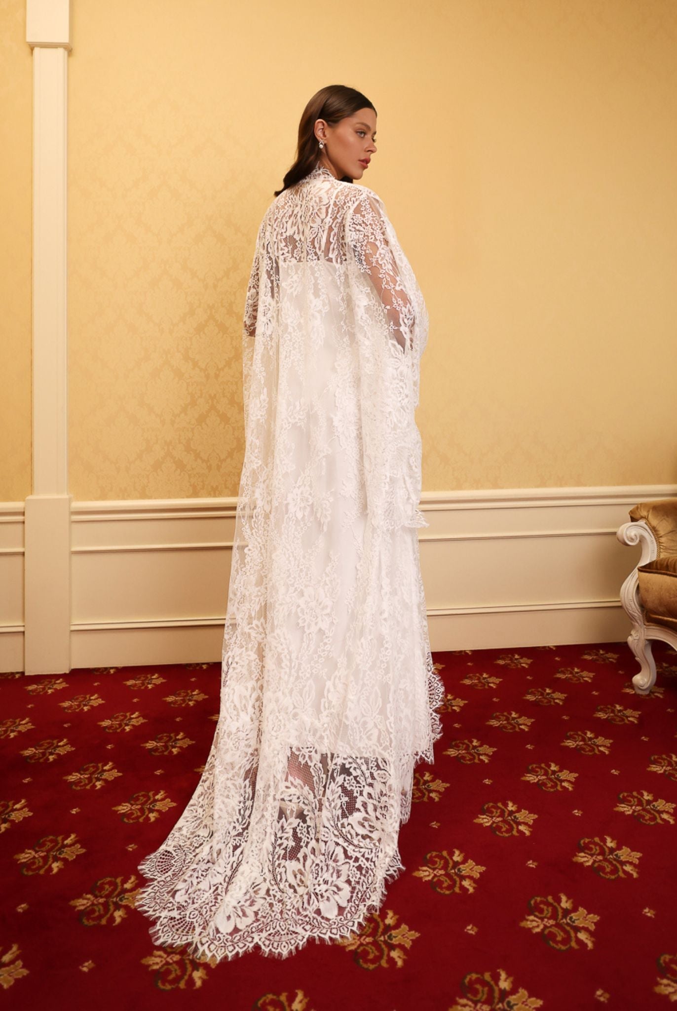 Model wearing a long white lace robe from kafemme on a red carpet background