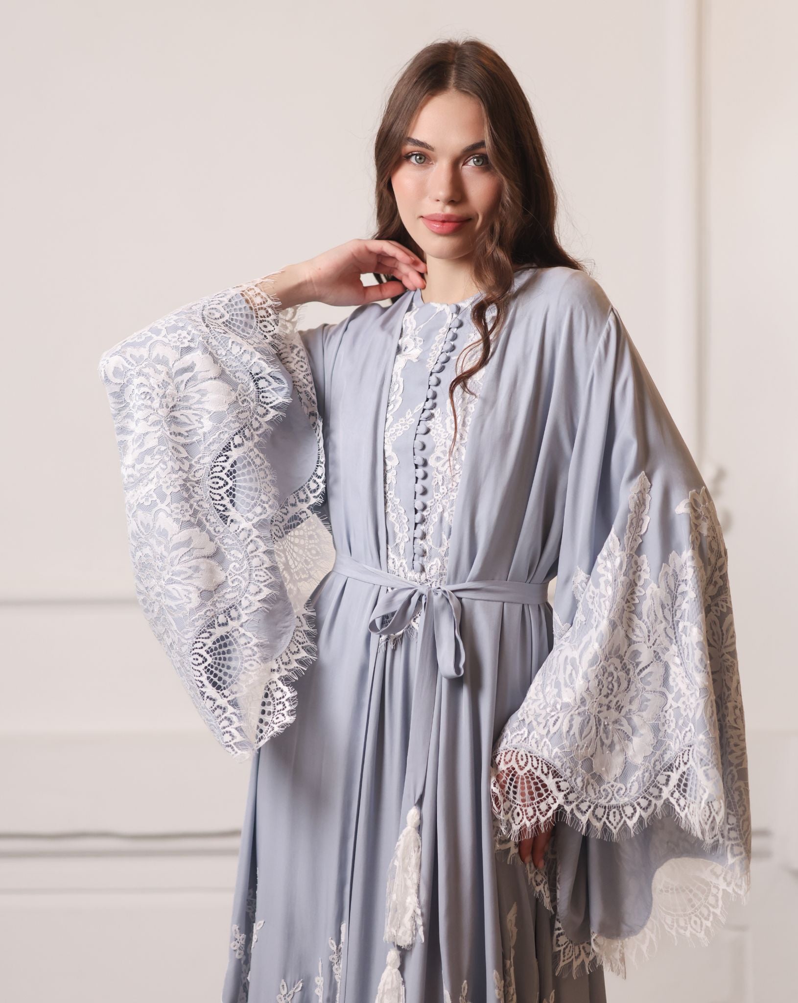 Waist-up shot of a robe tied with a tassel belt, highlighting the defined silhouette and lace details.