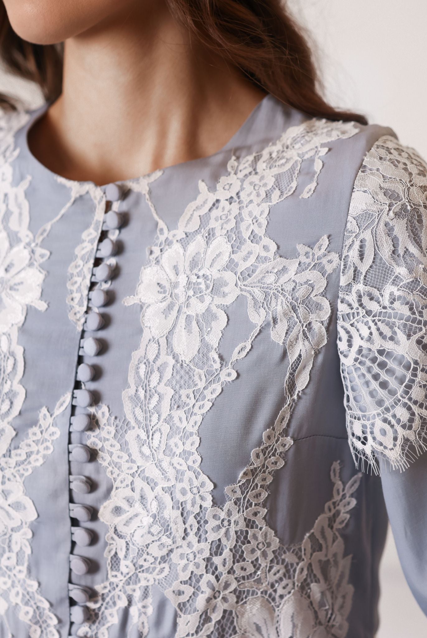 Close-up of fabric-covered buttons and French lace on a nightdress, perfect for breastfeeding access.