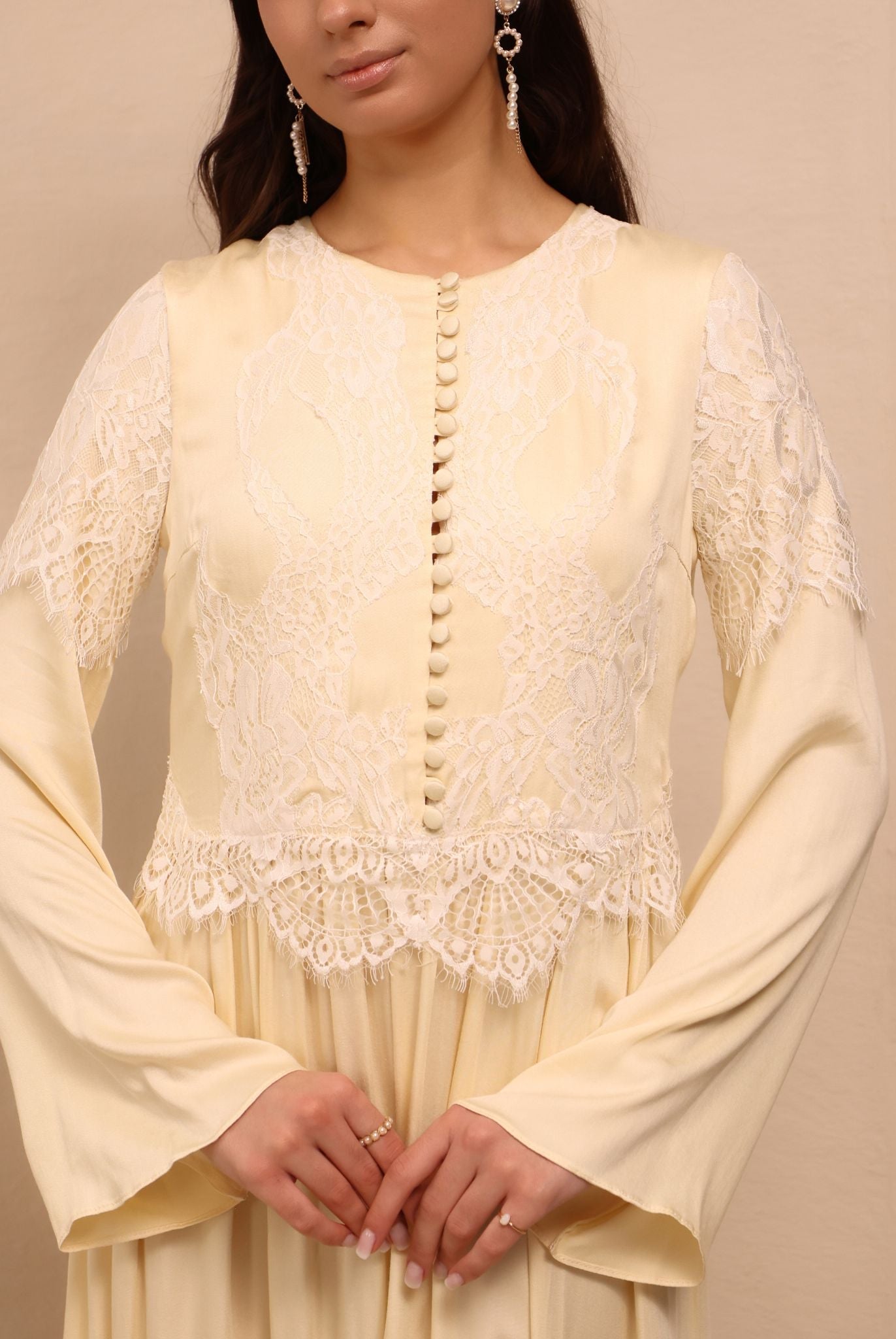 A close-up focusing on the French lace with floral patterns and small buttons covered in matching fabric.