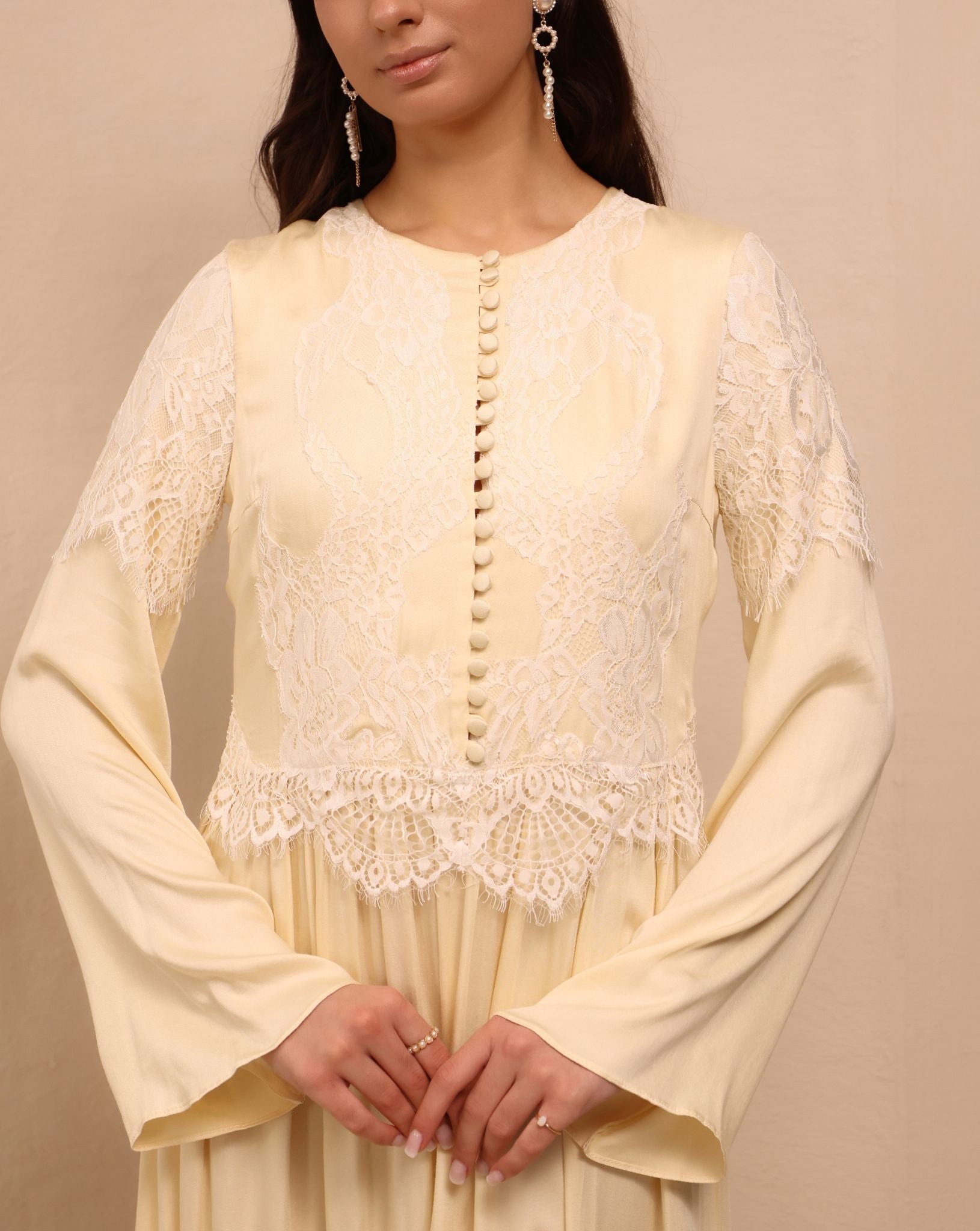 A close-up focusing on the French lace with floral patterns and small buttons covered in matching fabric.