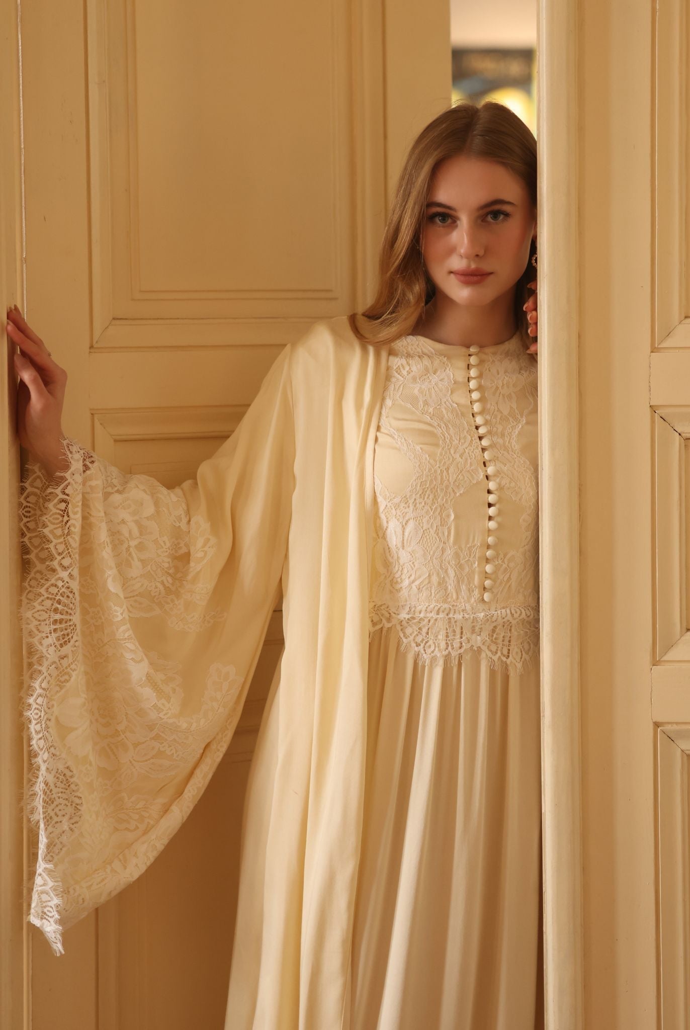 A mid-length shot in the doorway, highlighting the beautiful wide sleeves and the soft French lace detailing.