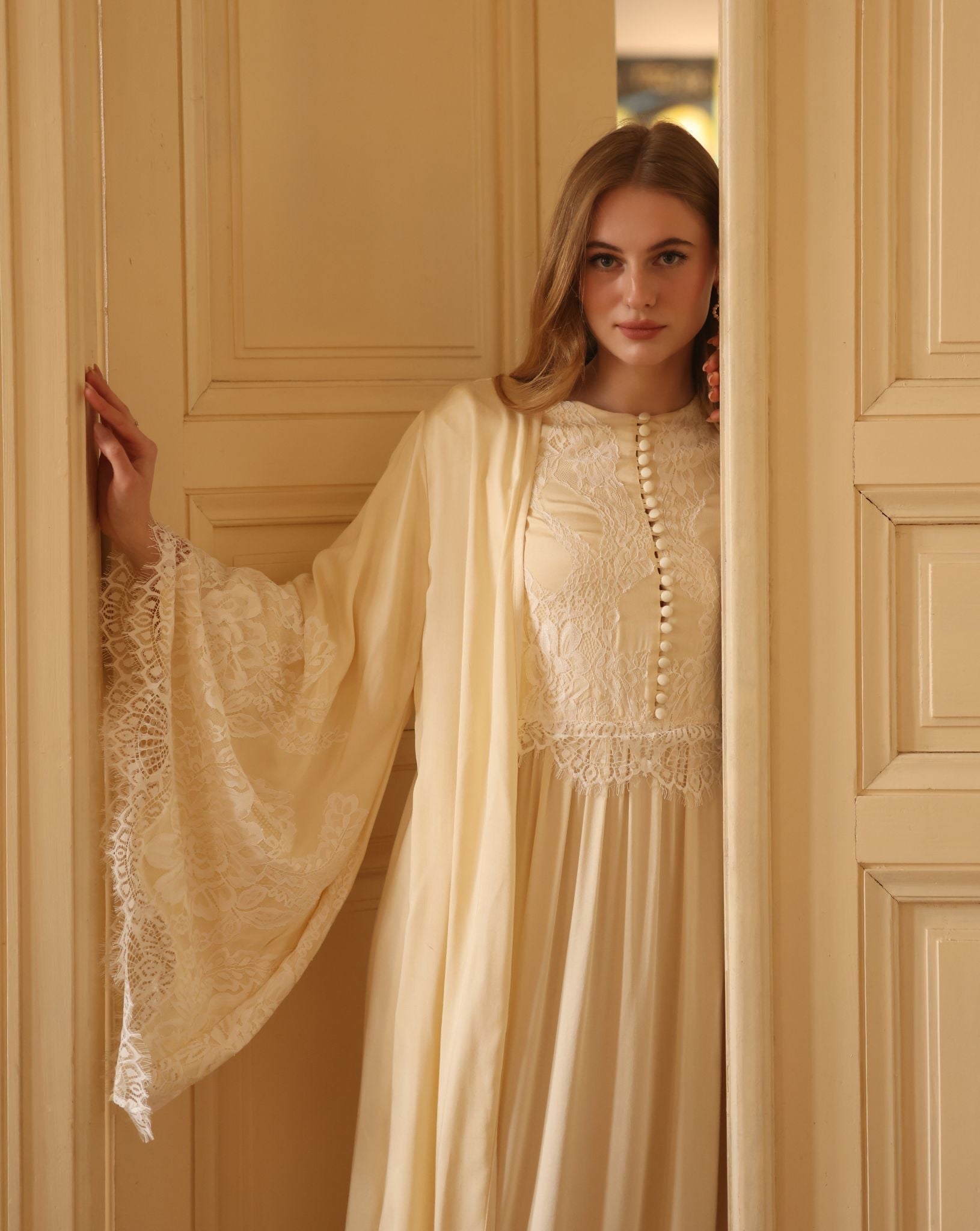 A mid-length shot in the doorway, highlighting the beautiful wide sleeves and the soft French lace detailing.