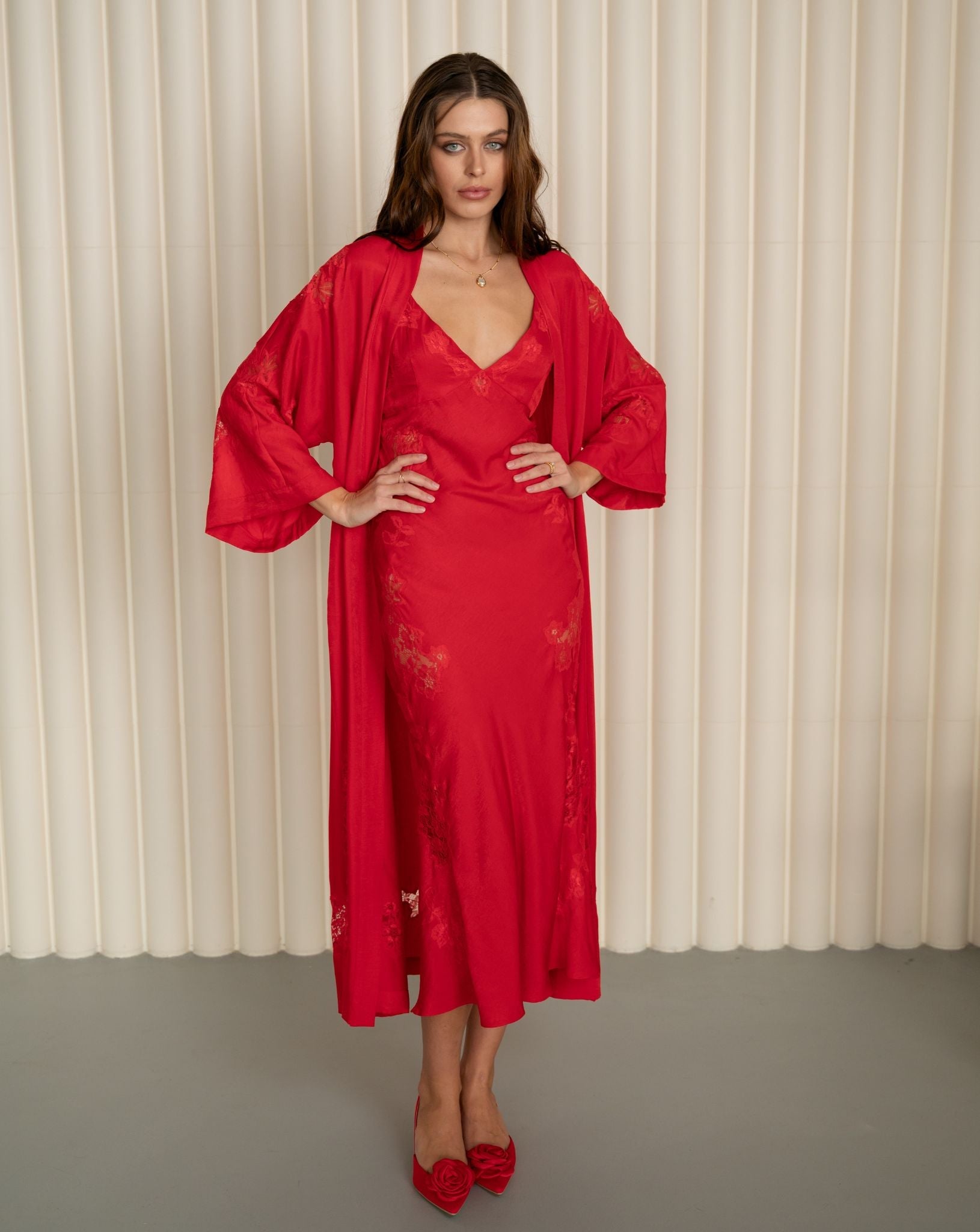 Full-length bridal look with hands on hips to display the wide sleeves and delicate lace inserts of the robe.