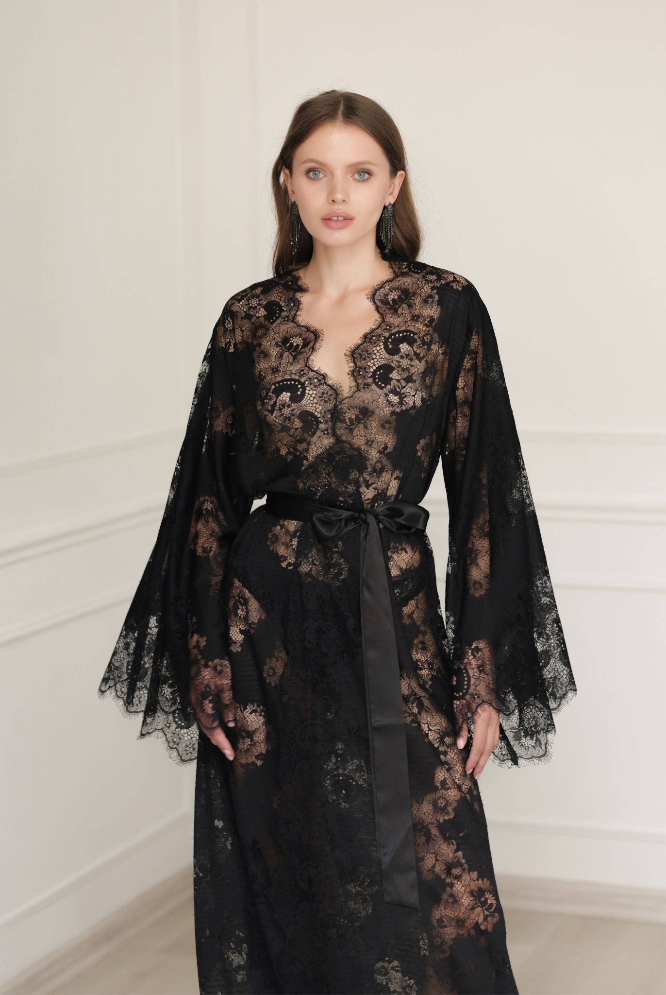 Mid-length shot of a flowing black robe in motion, highlighting the airy lace sleeves and elegant wrap-over style.