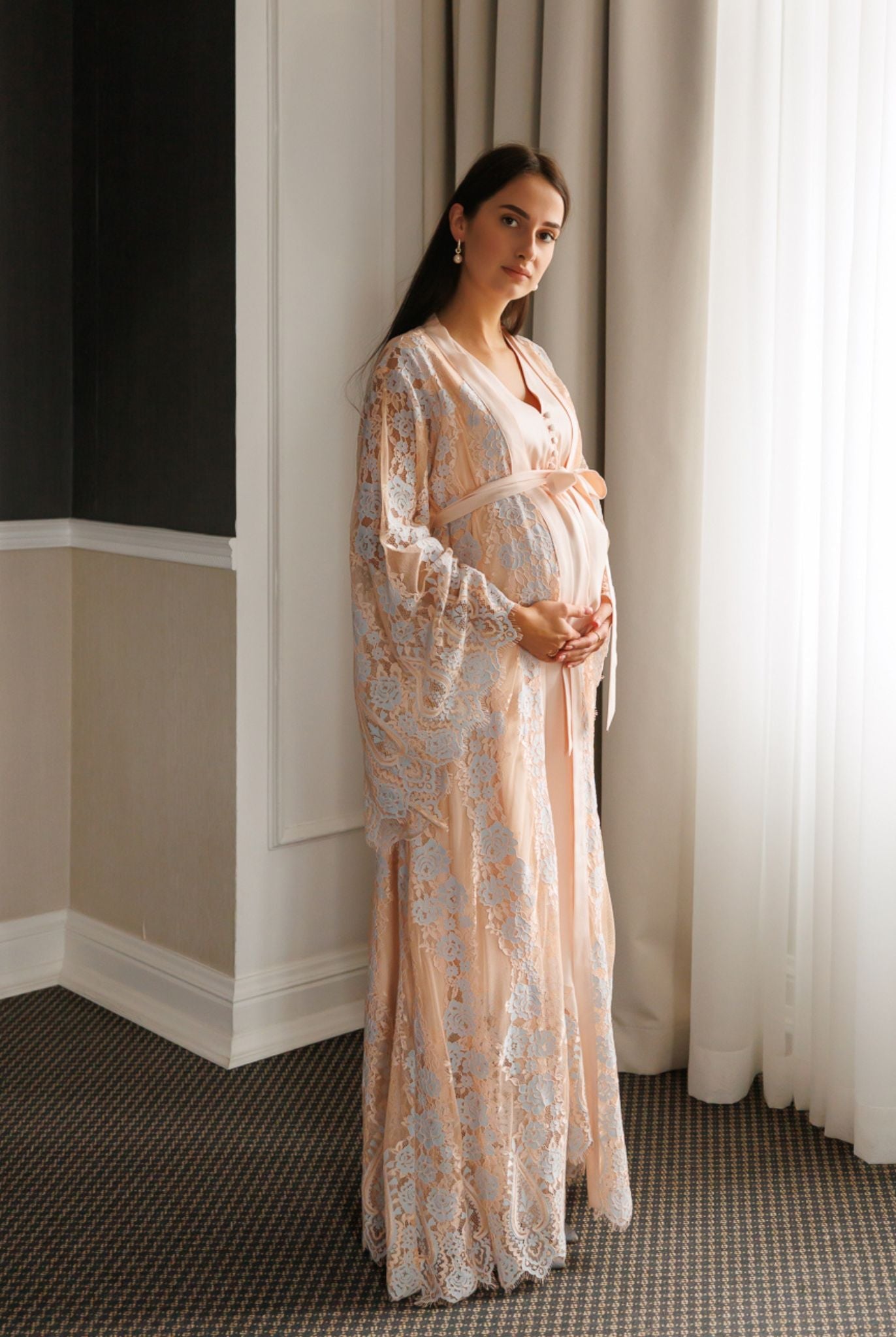 Standing full-length view of a pregnant woman in a Maternity Robe and Nightgown Set, gently holding her belly.