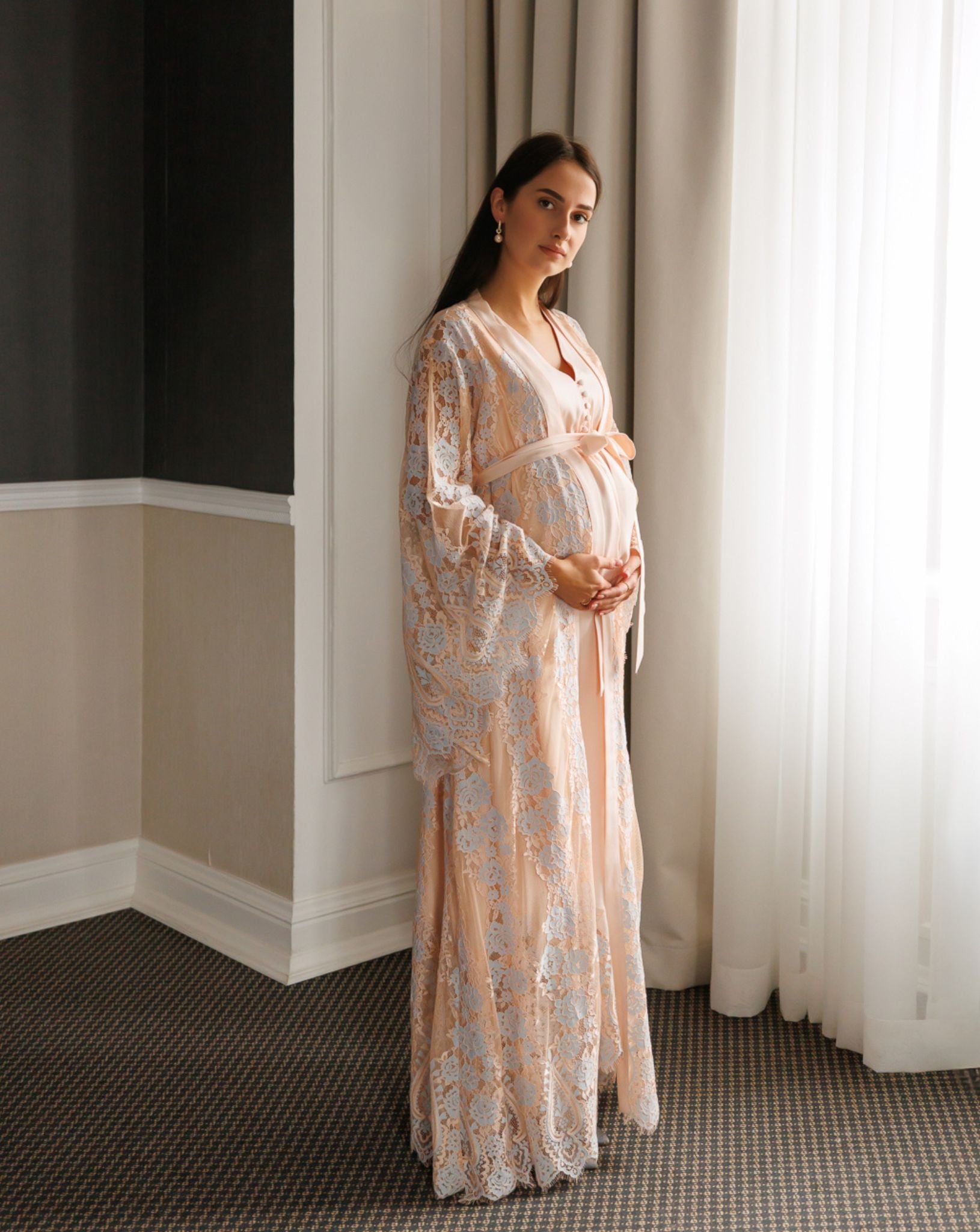 Standing full-length view of a pregnant woman in a Maternity Robe and Nightgown Set, gently holding her belly.