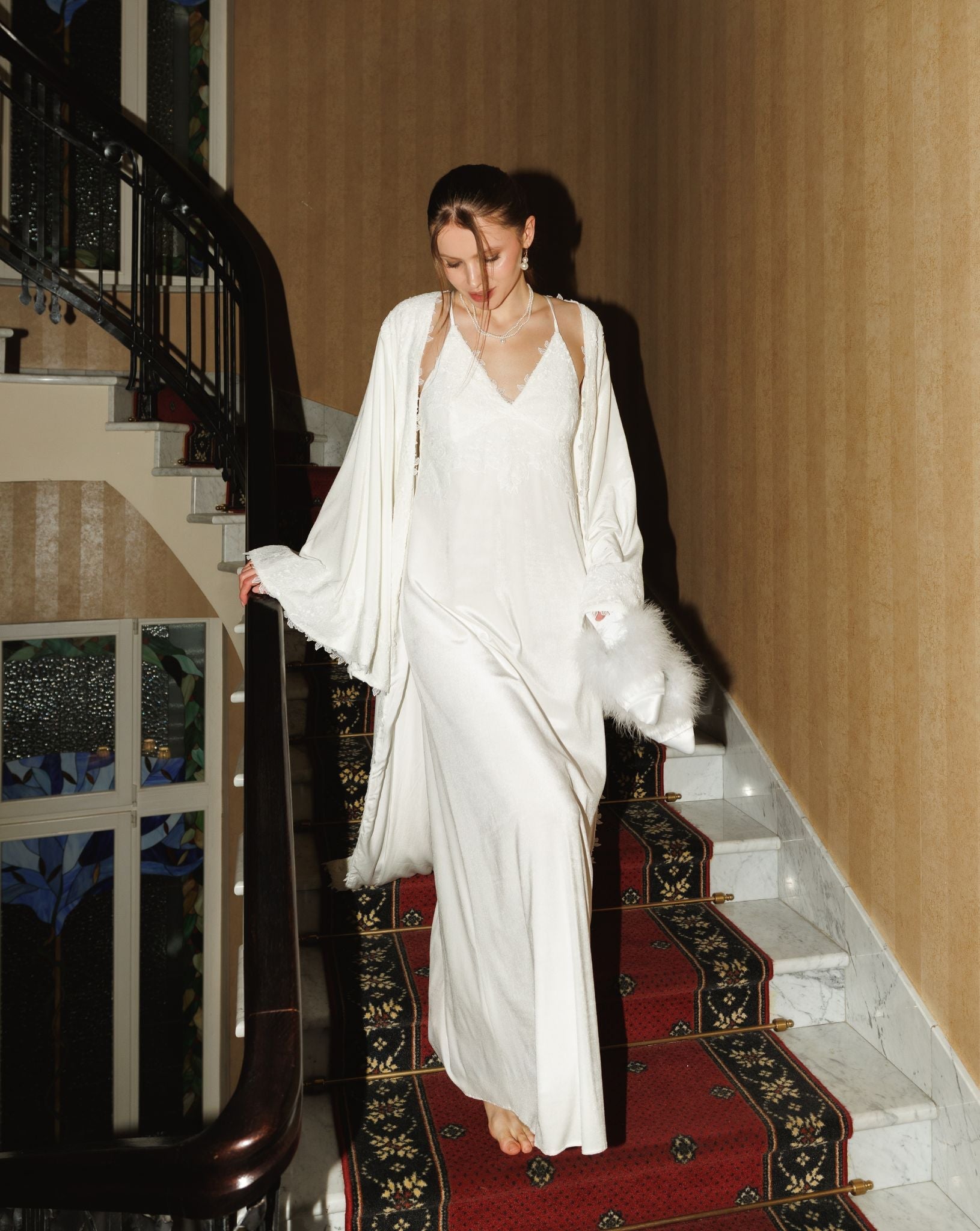A graceful figure in a flowing velvet ensemble descends a staircase, embodying luxury and fluid motion.