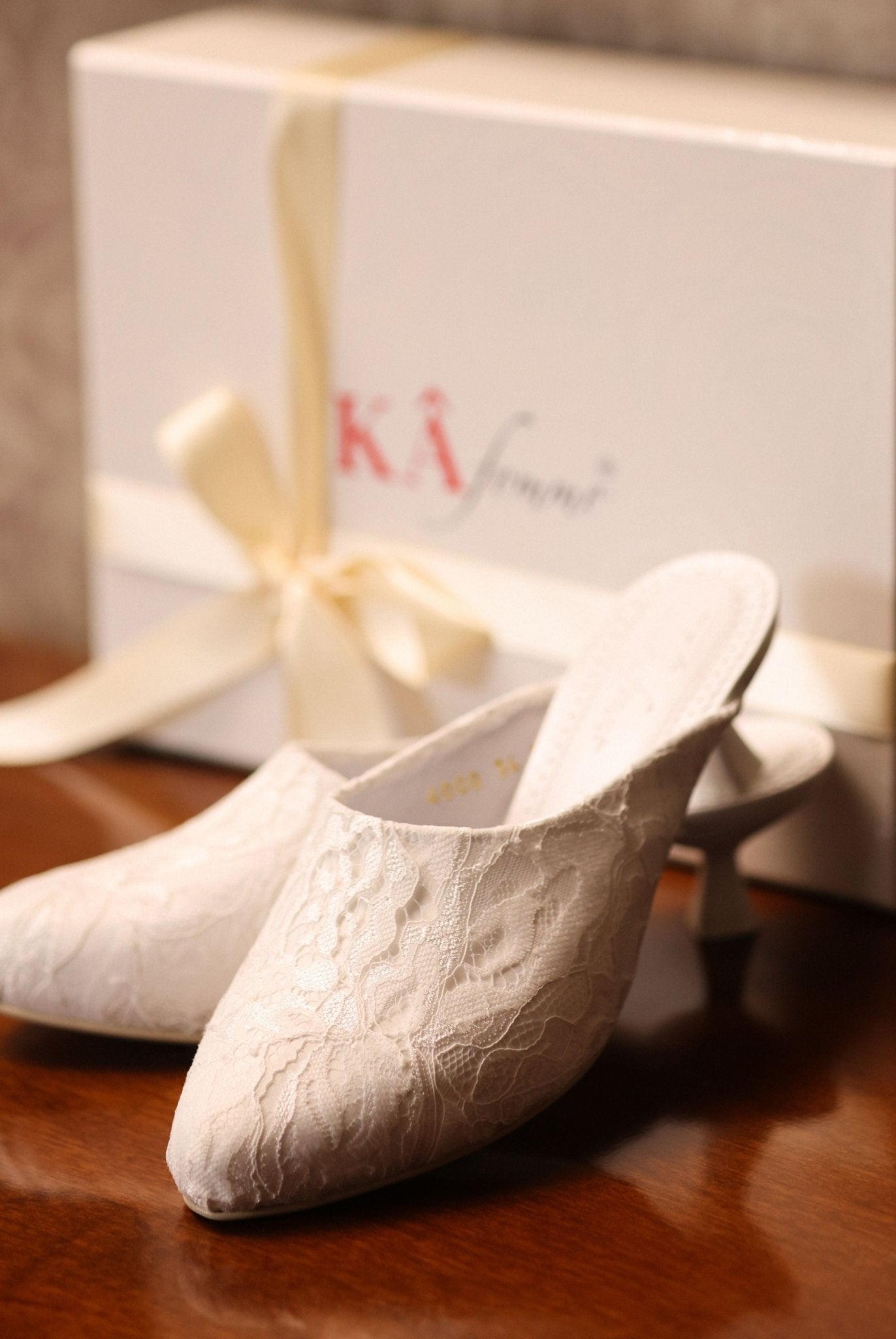 Elegant footwear presented next to its branded box, reflecting a refined essential made for special moments.