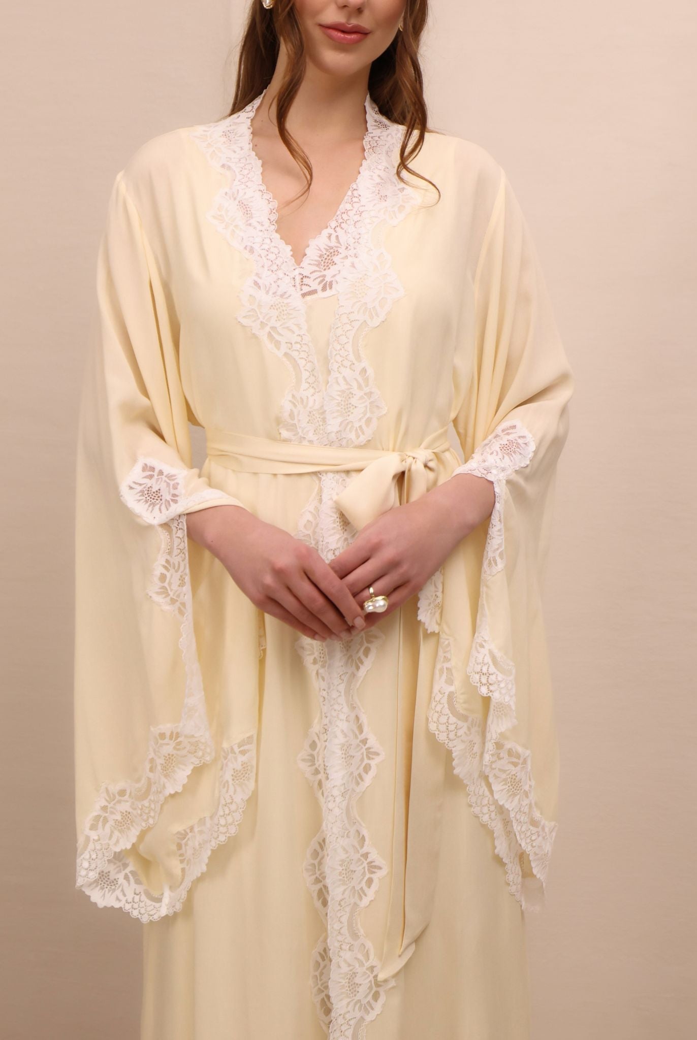 A mid-length shot focusing on the intricate lace and sleeve slits that add movement to the elegant silhouette.