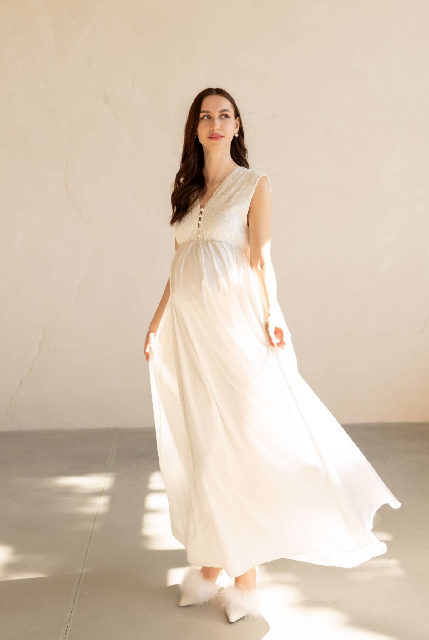 Front view of a white maternity nightdress with a loose fit, V-neckline, and delicate lace along the hem.