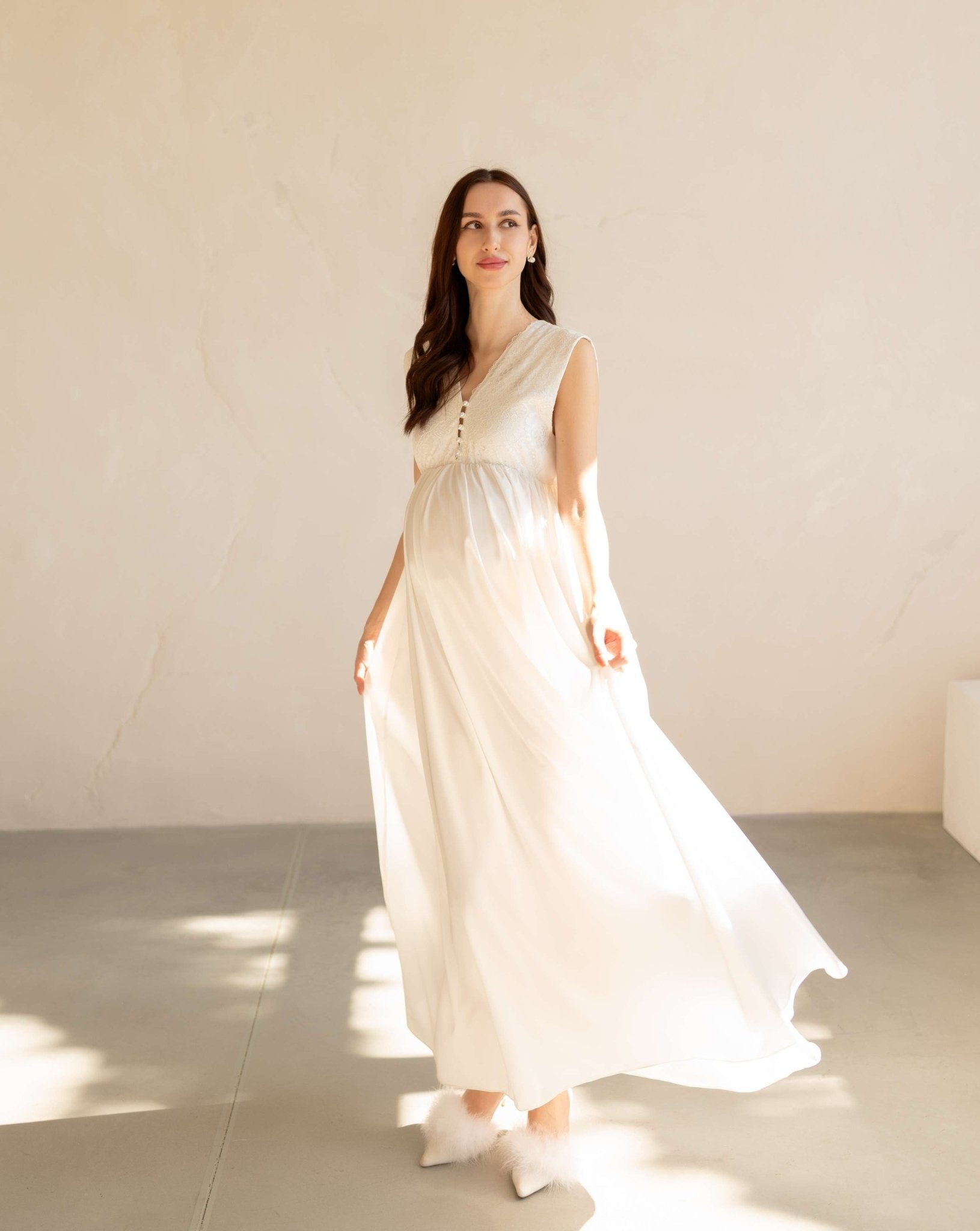 Front view of a white maternity nightdress with a loose fit, V-neckline, and delicate lace along the hem.