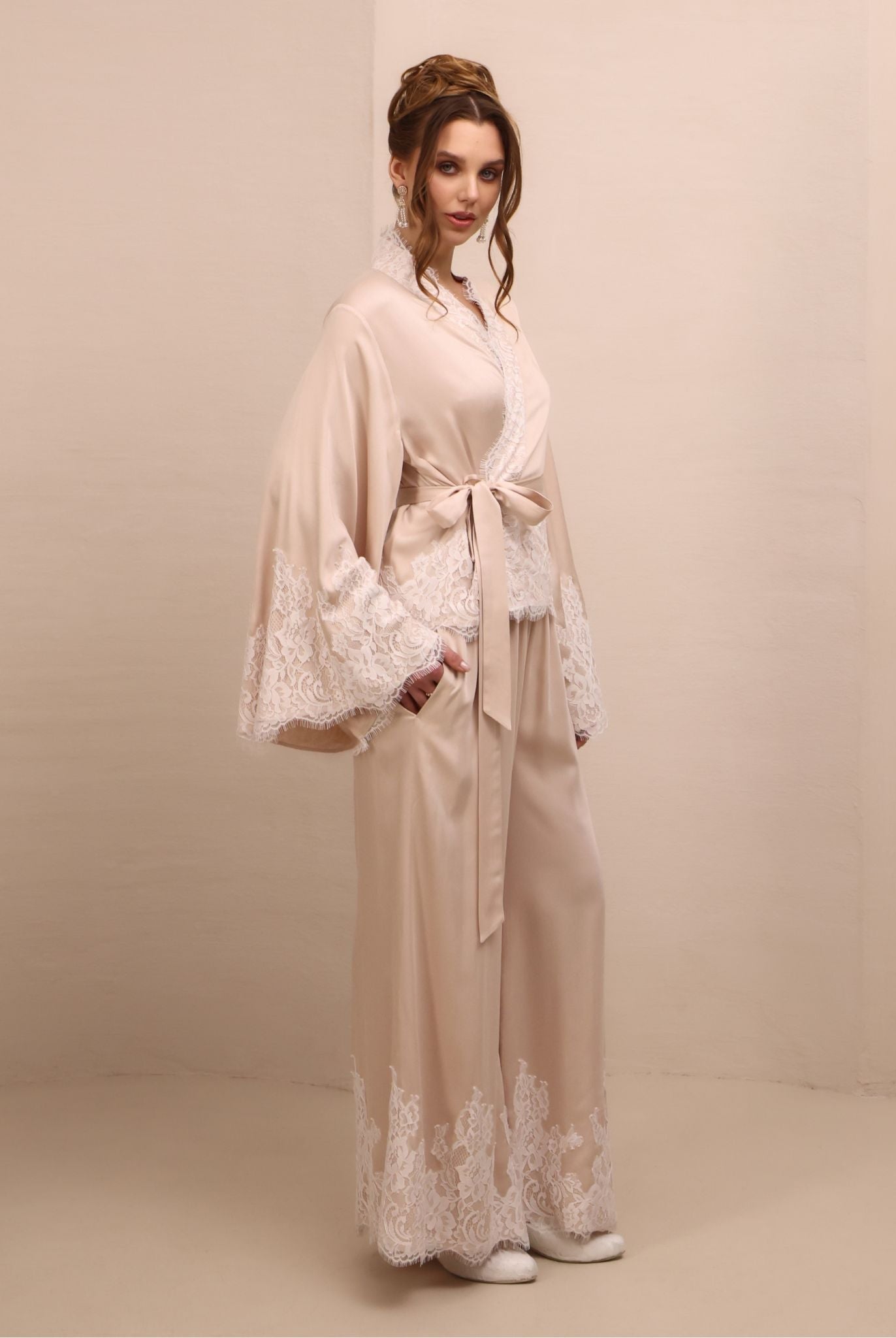 Side shot with a raised arm, showcasing the long sleeves with lace-embellished edges and refined finish.