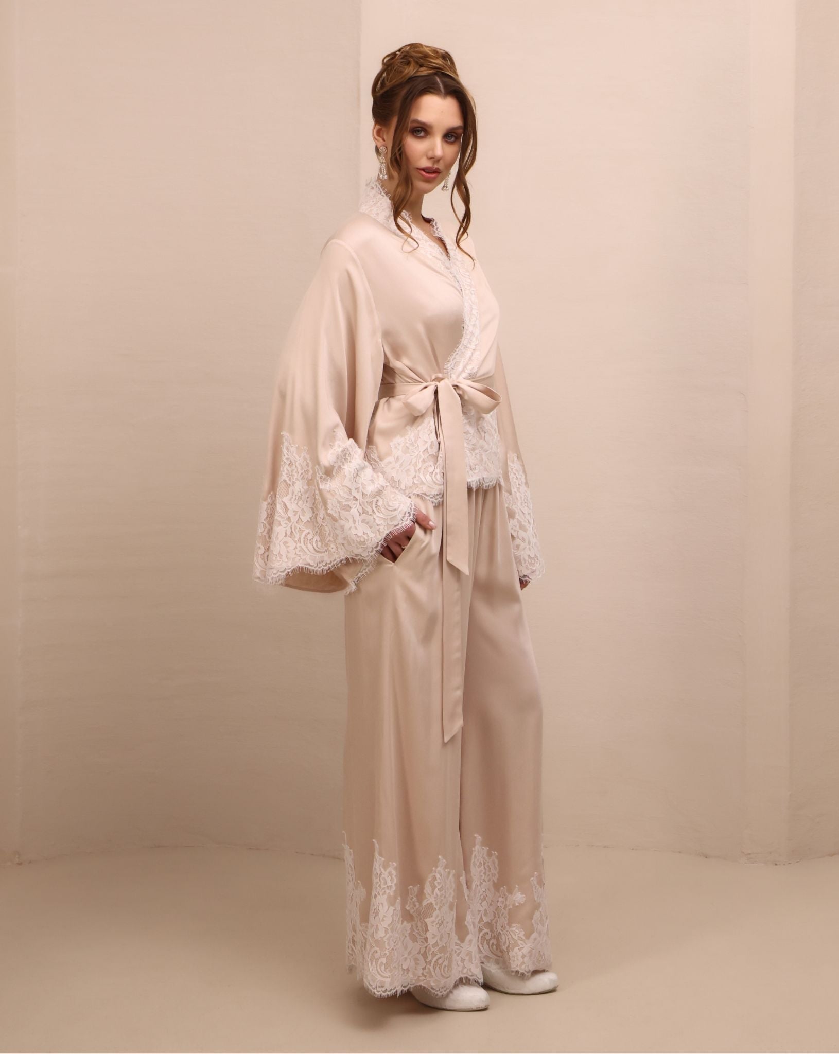 Side shot with a raised arm, showcasing the long sleeves with lace-embellished edges and refined finish.