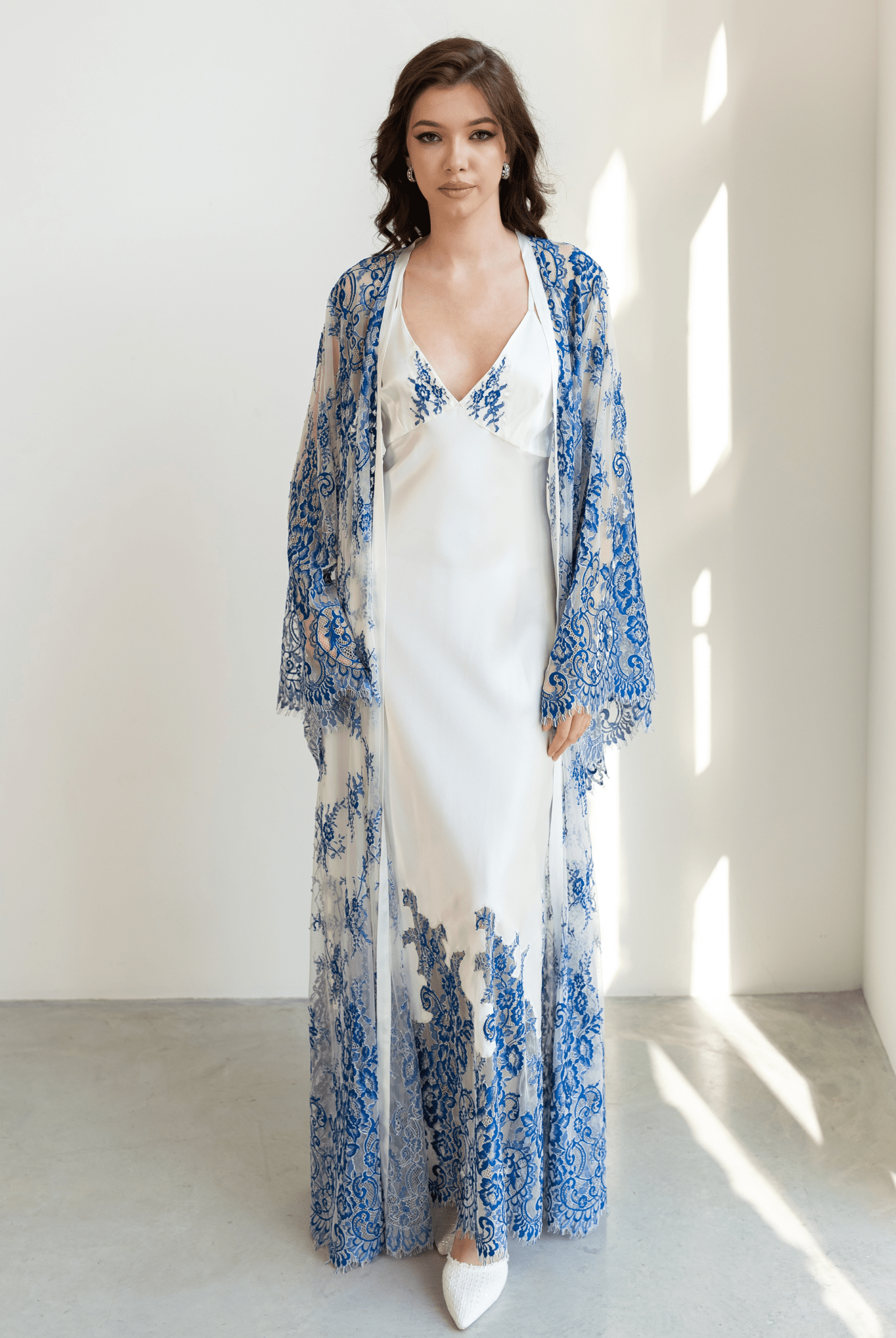 Model in long blue and white lace robe layered over silk nightgown