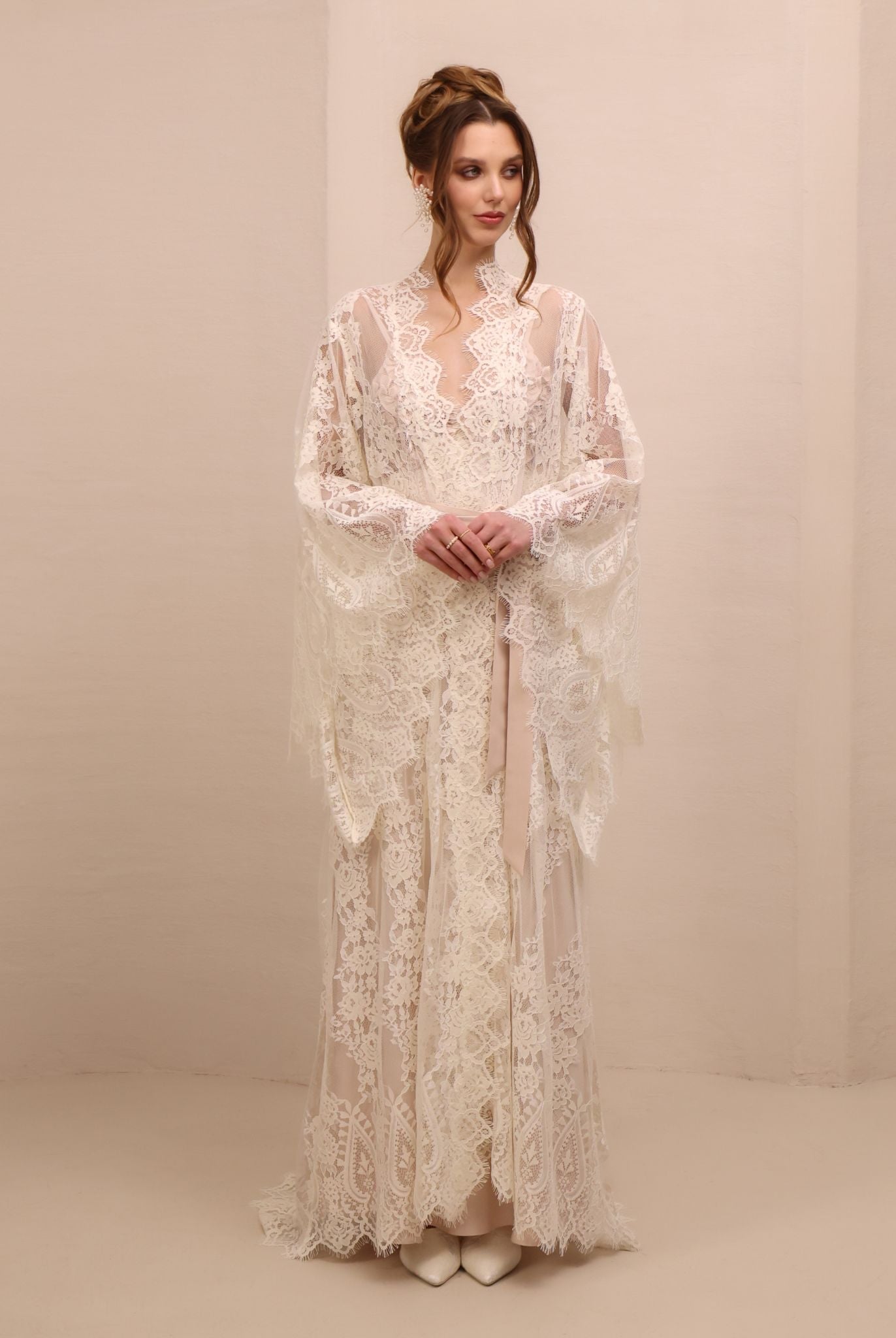 A poised frontal shot focusing on the wide sleeves of the lace robe, designed for elegance and presence.