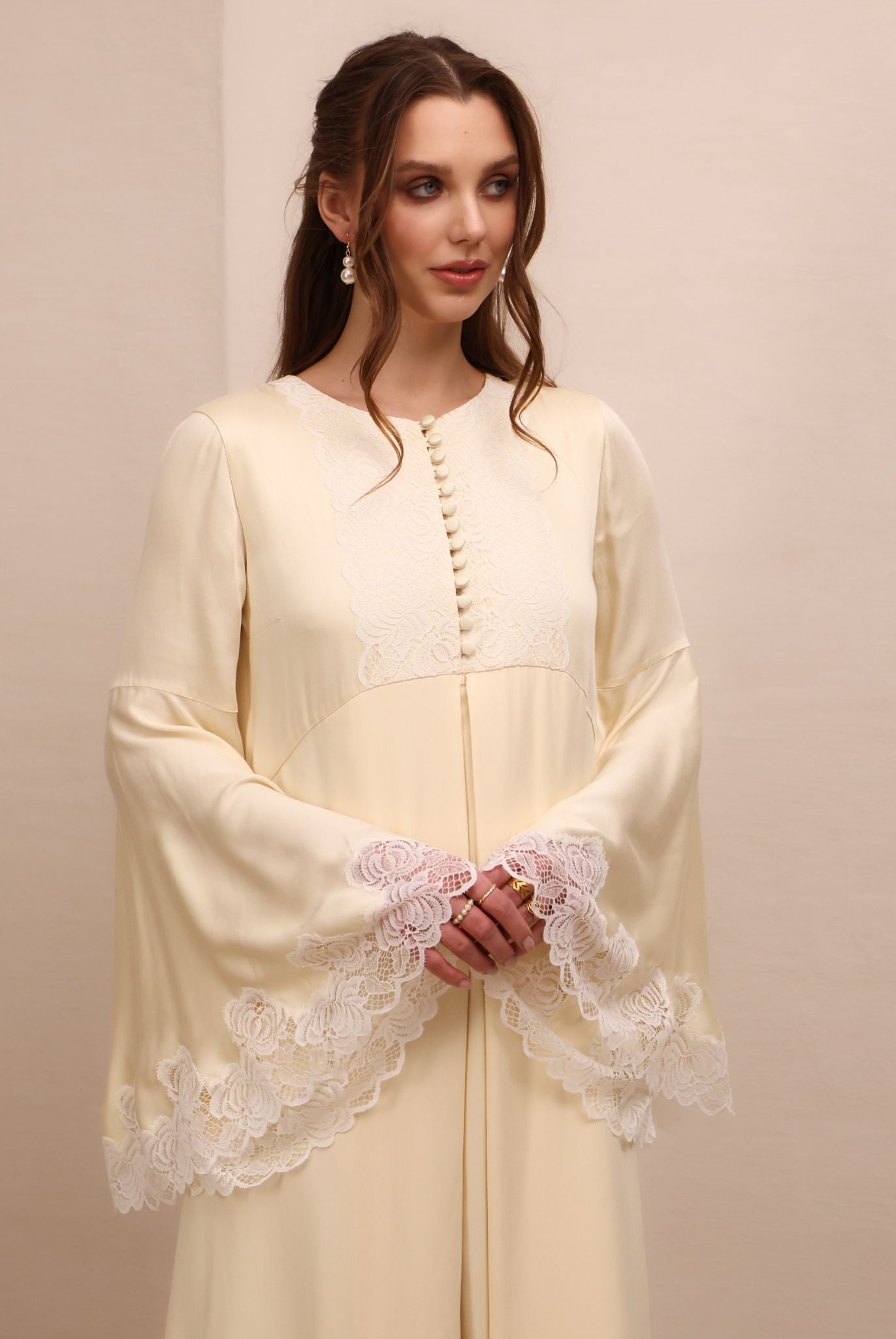 A mid-length shot focusing on the wide sleeves with fine lace that adds a romantic touch to every gesture.