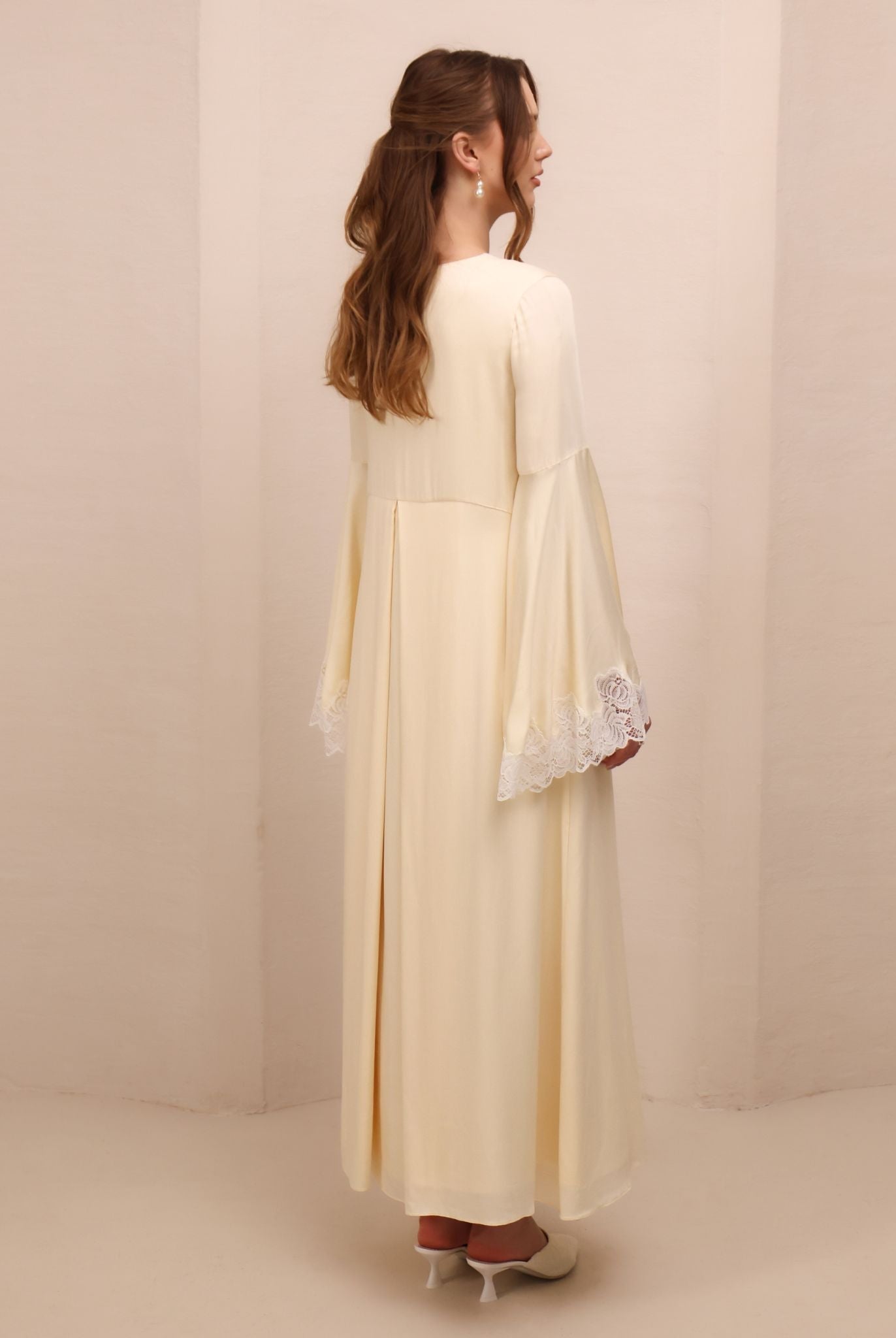 Rear view of the dress, highlighting the elongated silhouette and the airy, layered design of the skirt.