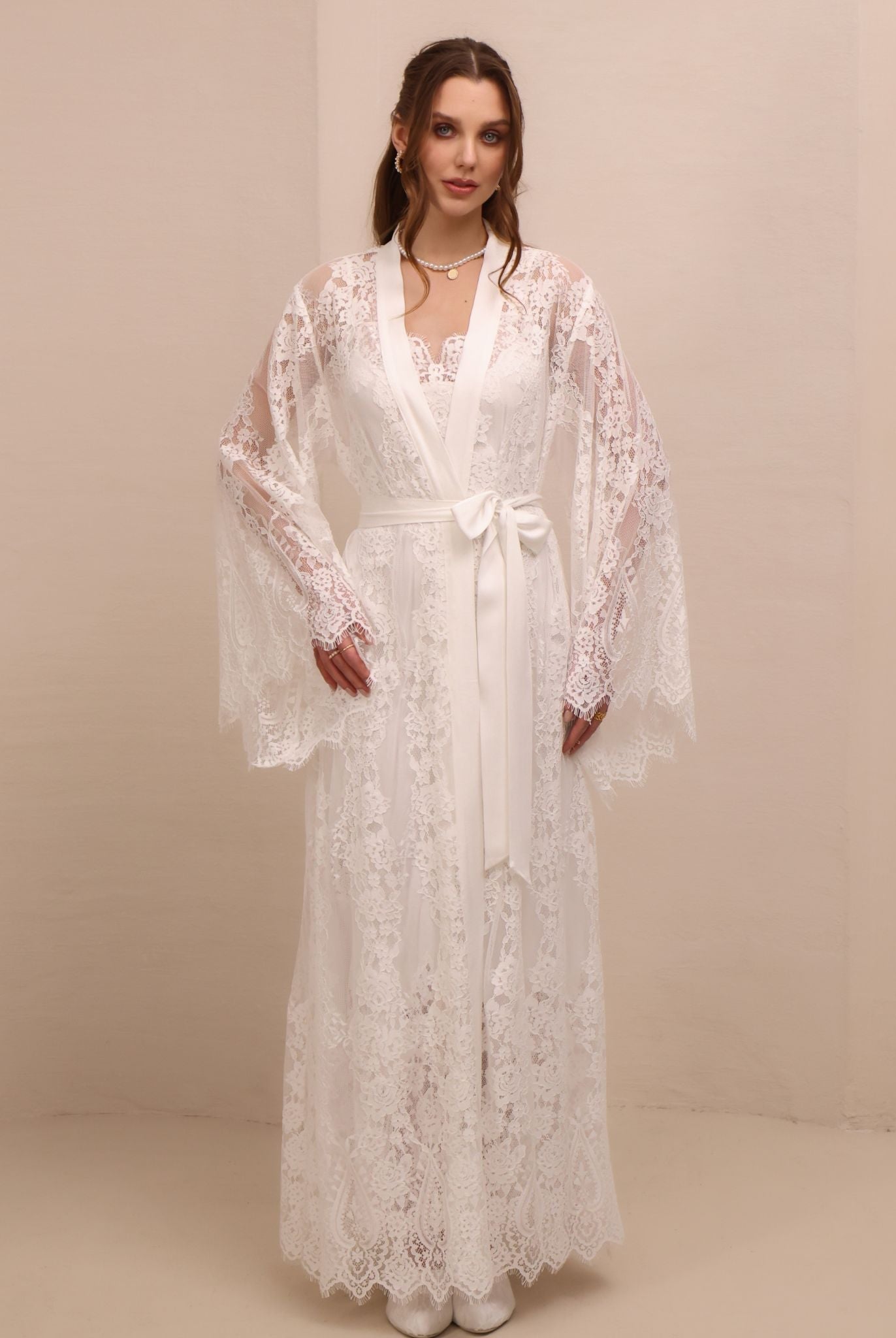 A frontal view with hands on hips, emphasizing the wide lace-finished sleeves and the defined waistline.