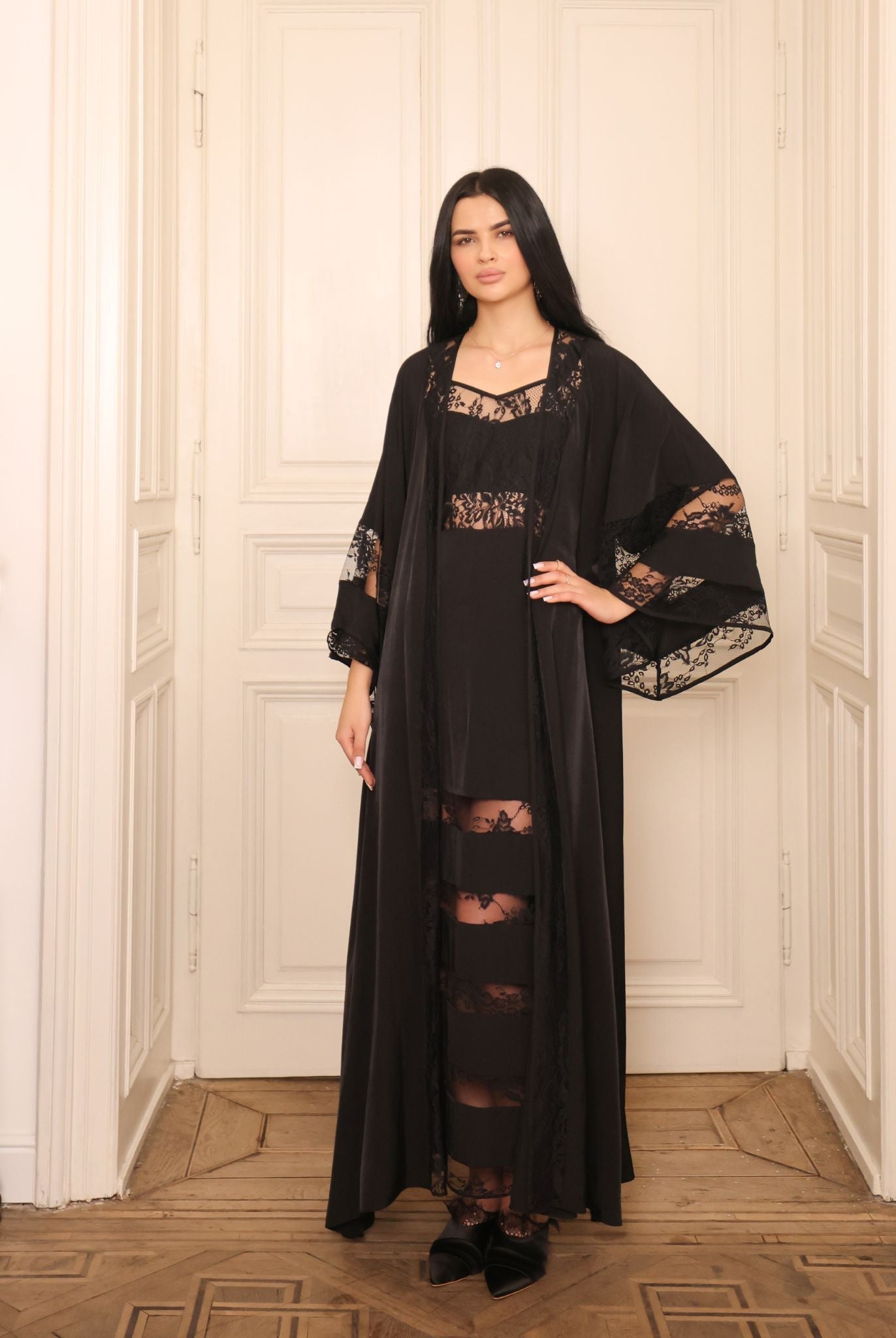 A sophisticated pose showcasing the delicate lace detailing at the sleeves and edges of the attire.