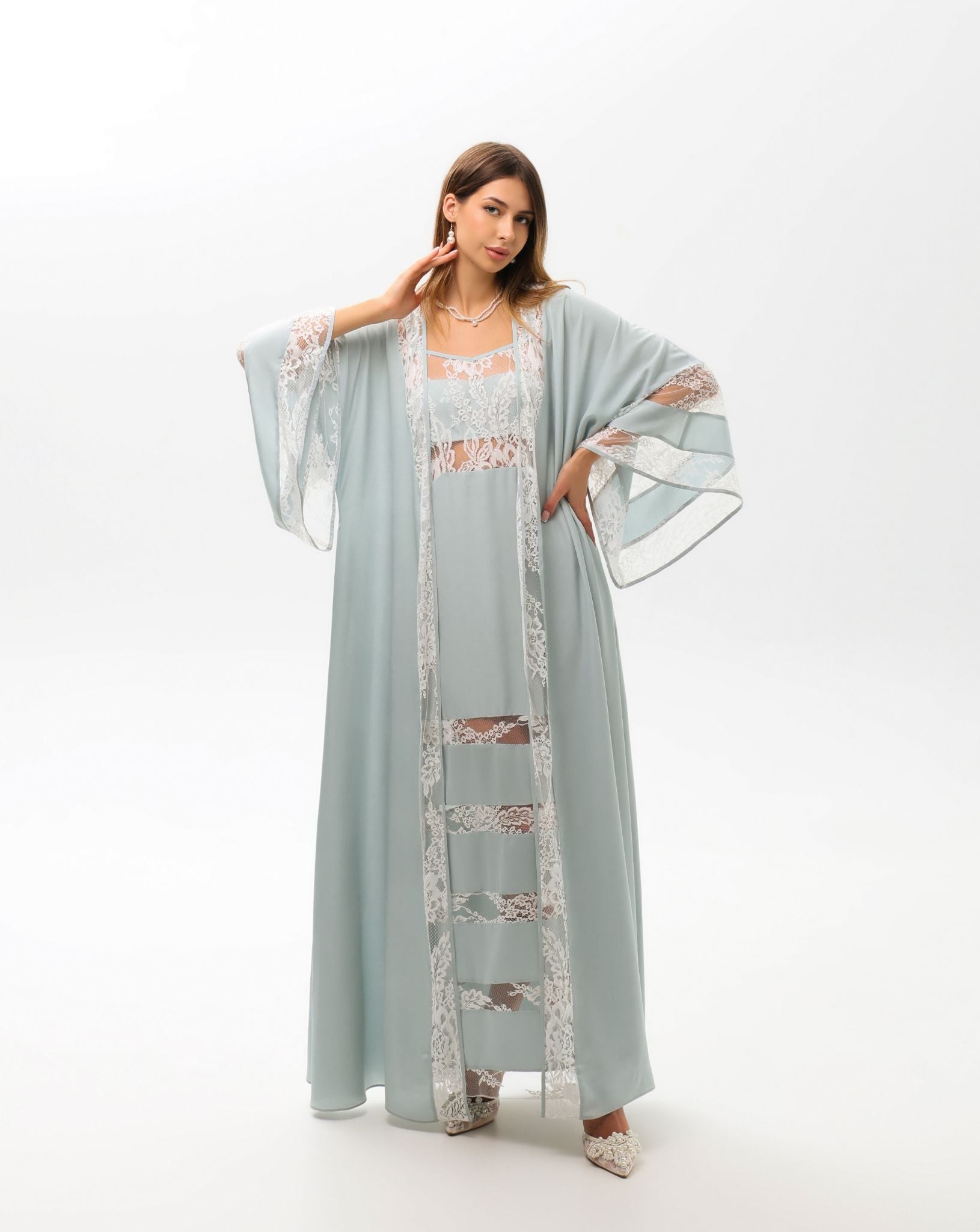 A sophisticated pose showcasing the delicate lace detailing at the sleeves and edges of the attire.