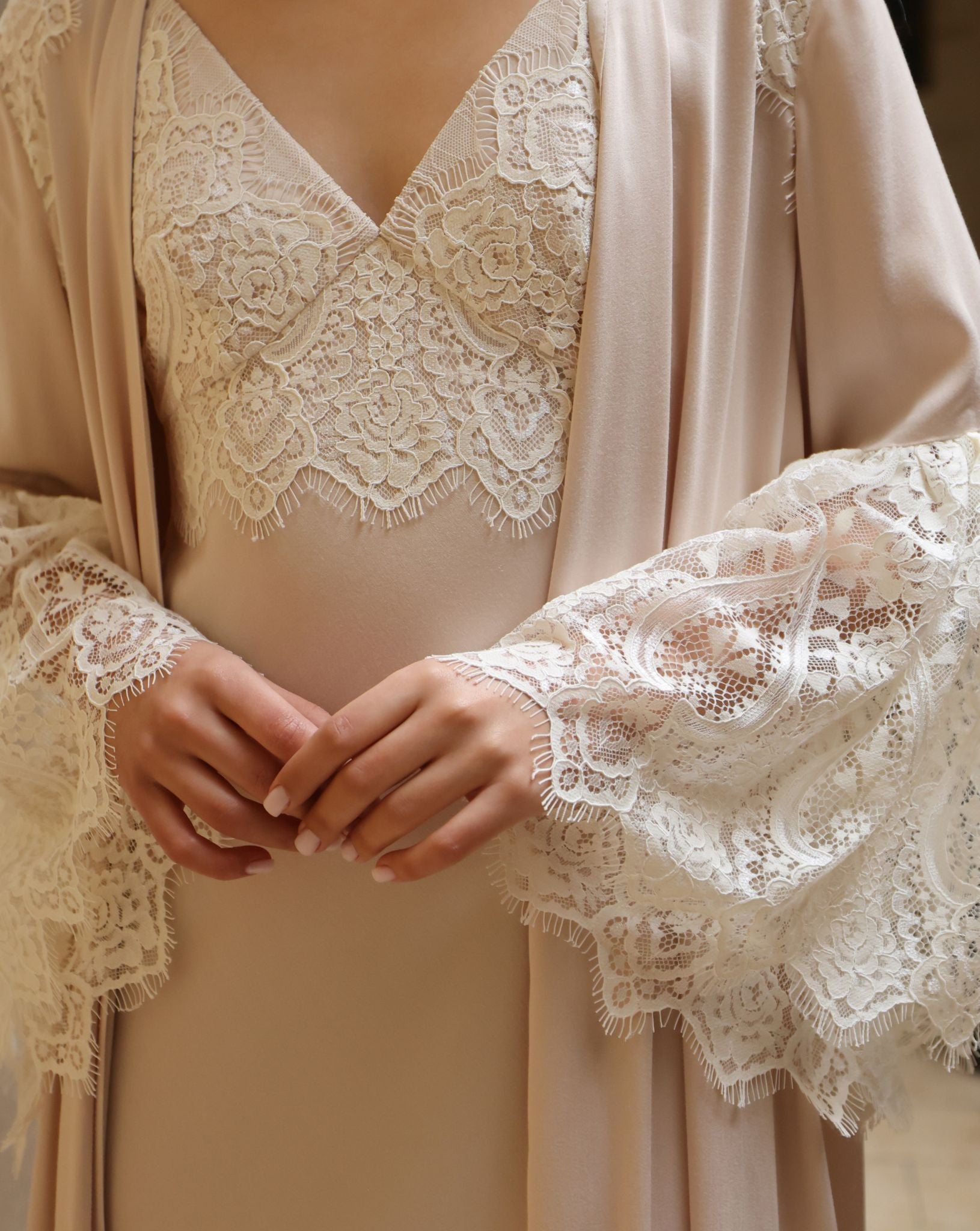 A close-up view from chest to hips, showcasing the delicate lace framing the neckline and the refined sleeve details.