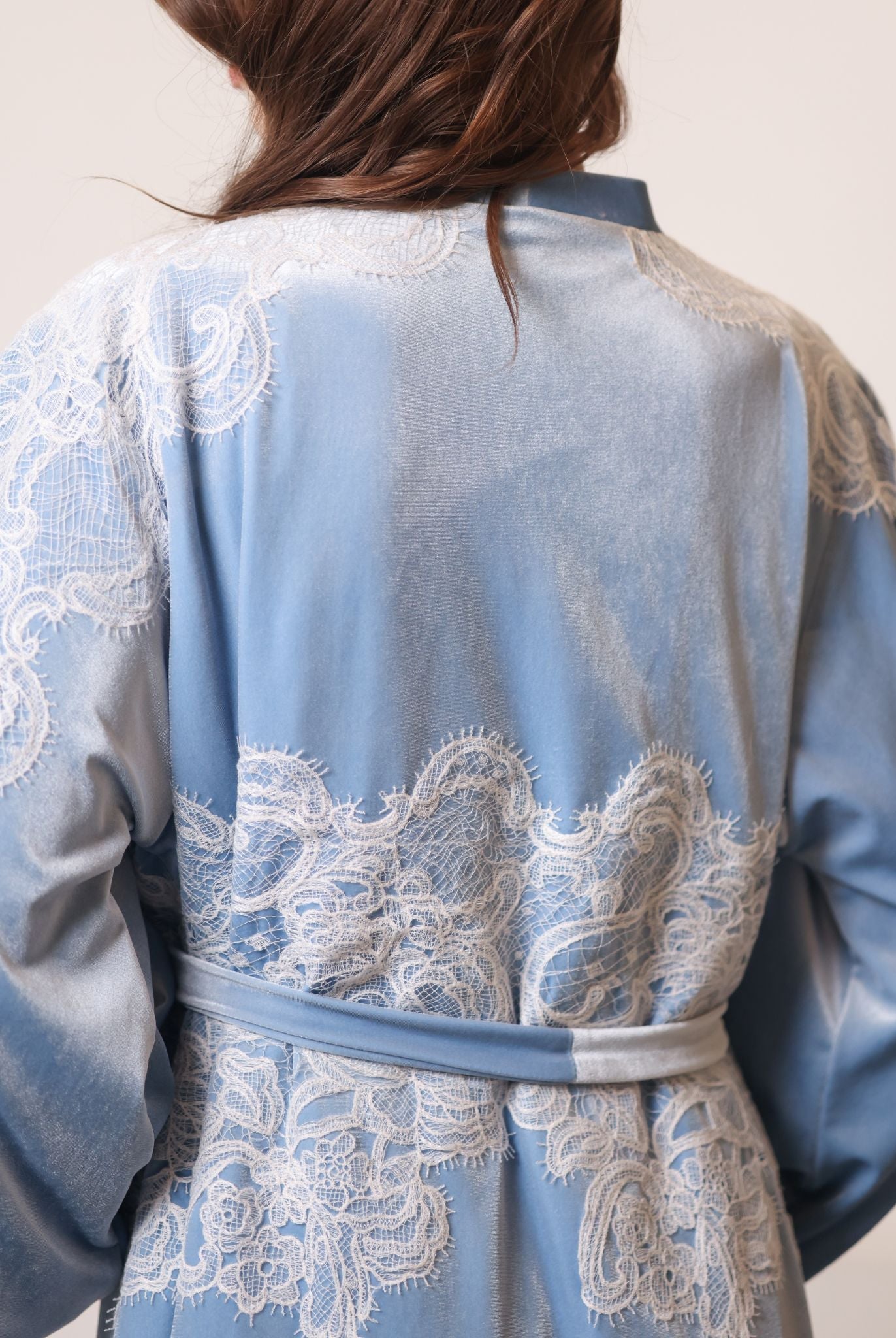Back view detail showcasing the ivory corded lace inserts on the shoulders of the luxurious blue robe.