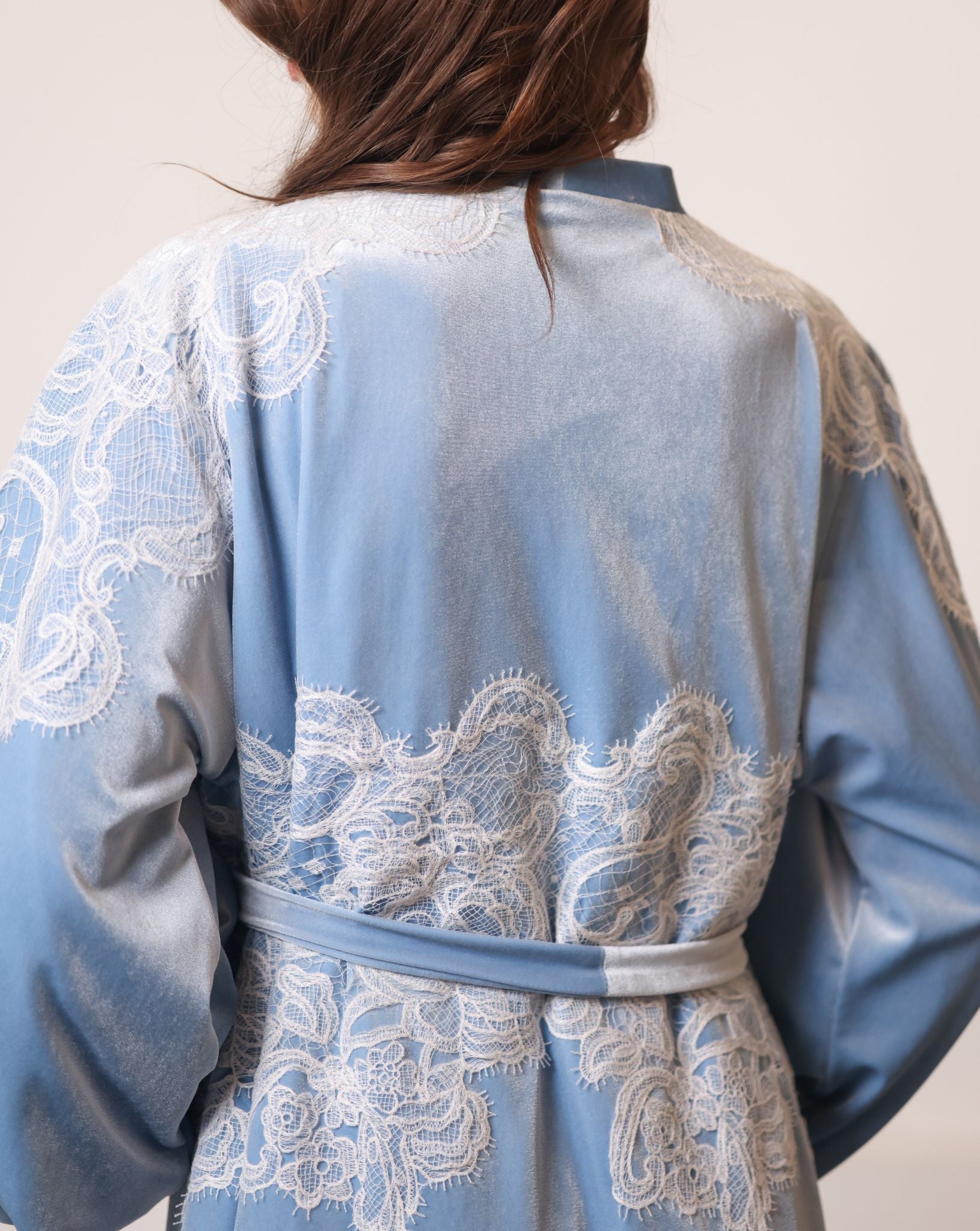 Back view detail showcasing the ivory corded lace inserts on the shoulders of the luxurious blue robe.