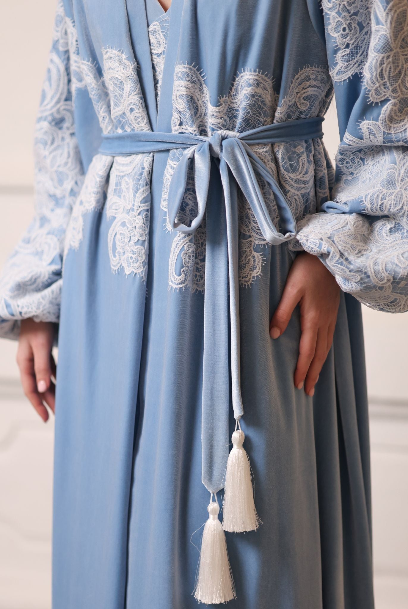 Close-up of a velvet tie at the waist, illustrating the elegant wrap-over style and rich texture of the garment.