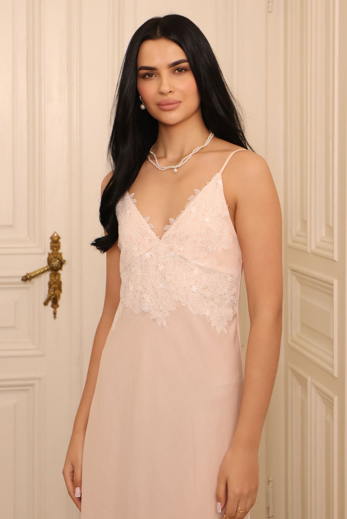 Mid-length shot focusing on the intricate lace at the neckline, illustrating the romantic restraint of the design.