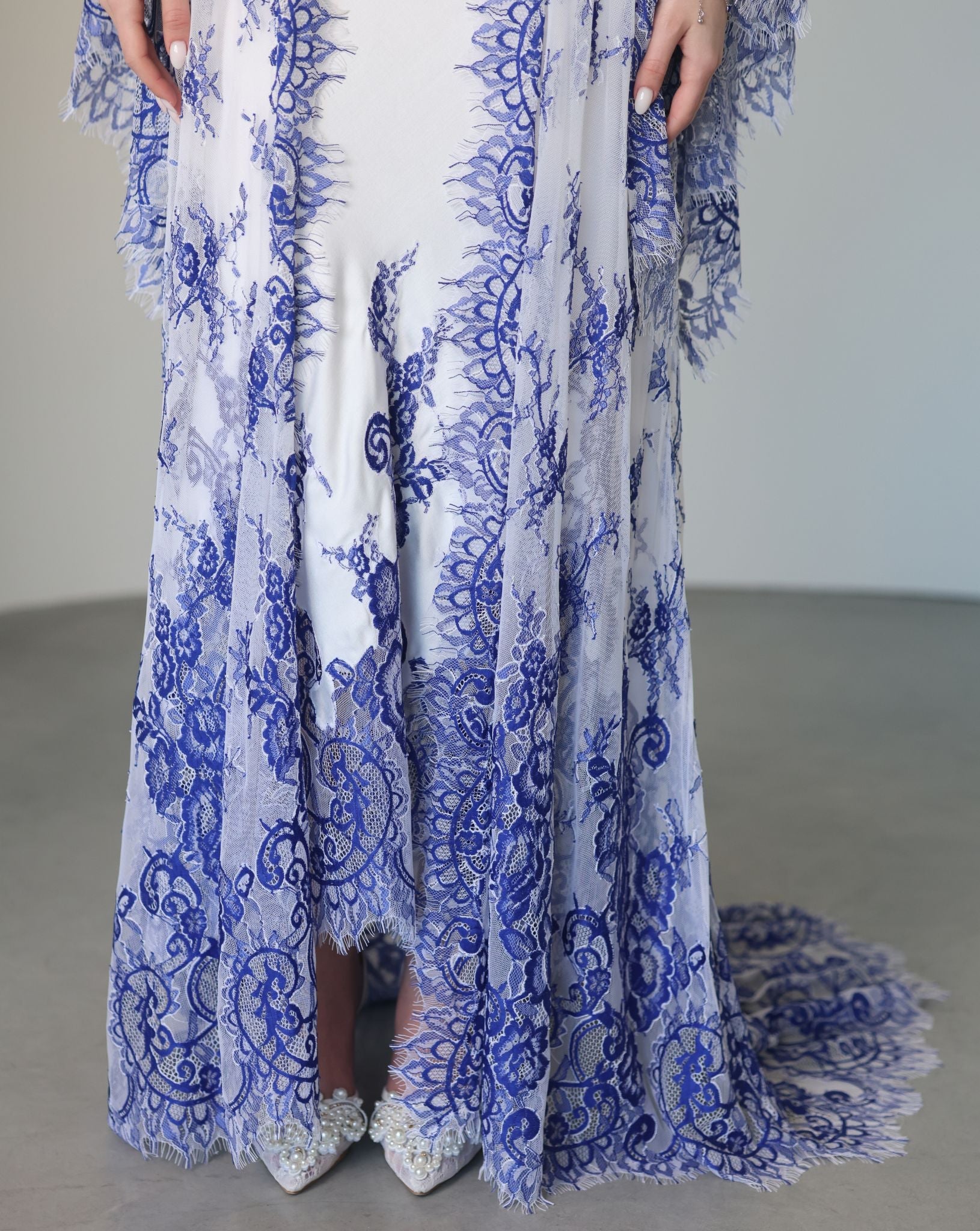 A detailed frontal view of the hem, focusing on how the intricate lace beautifully edges the gown and the robe.