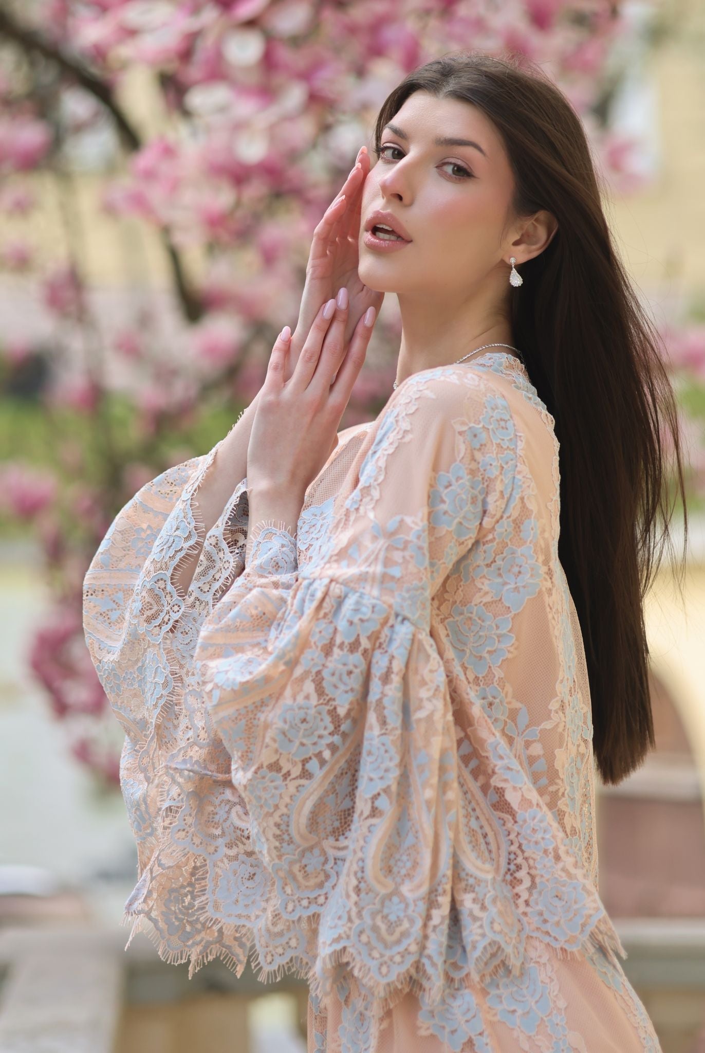 An artistic shot of a woman in a pajama set against a blooming magnolia, blending natural beauty with refined home wear.