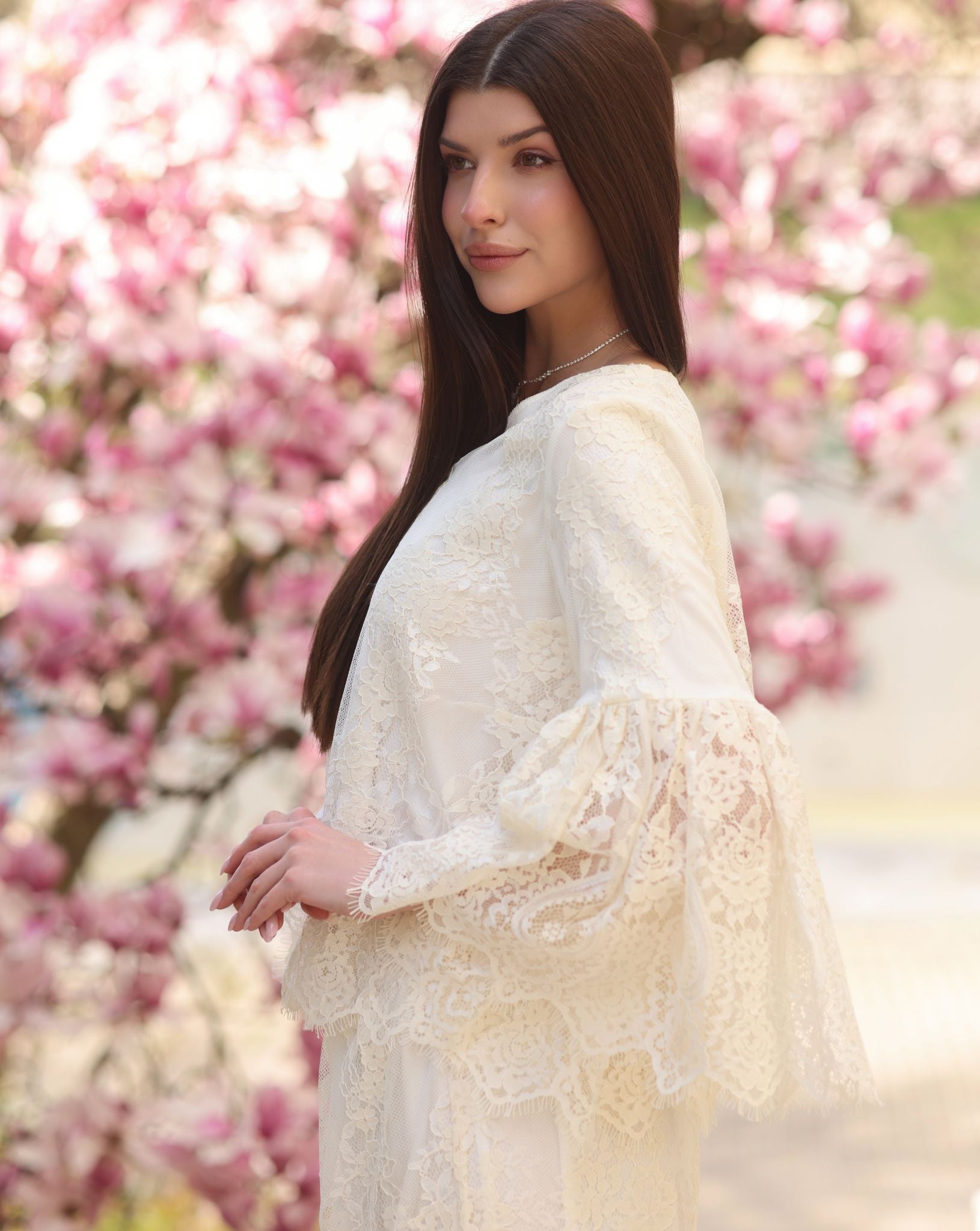 A side view from head to hips, highlighting the wide statement sleeves layered with intricate lace for a refined touch.