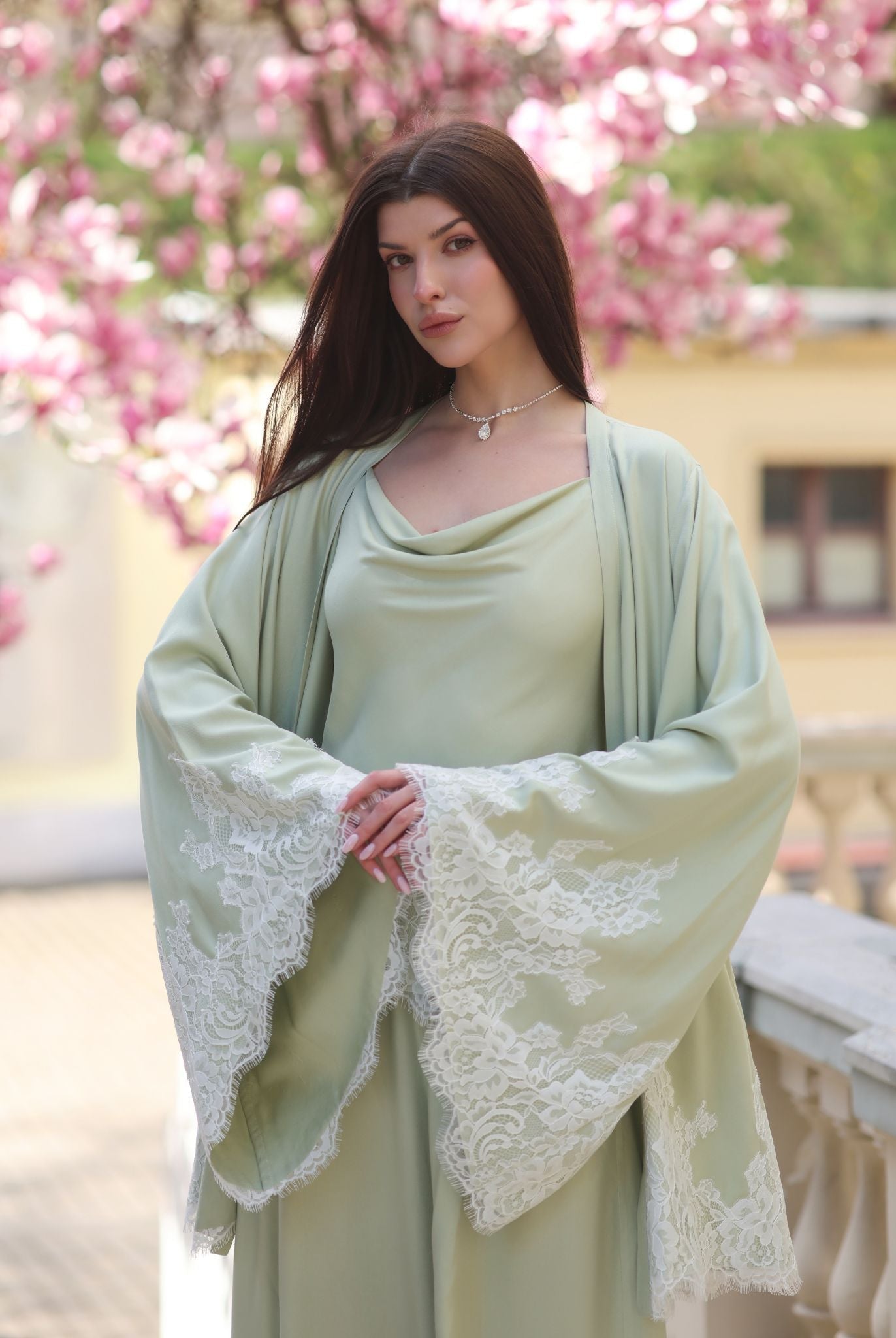 A mid-length shot of the full Pyjamas set with hands on the waist to highlight the wide, lace-embellished sleeves.