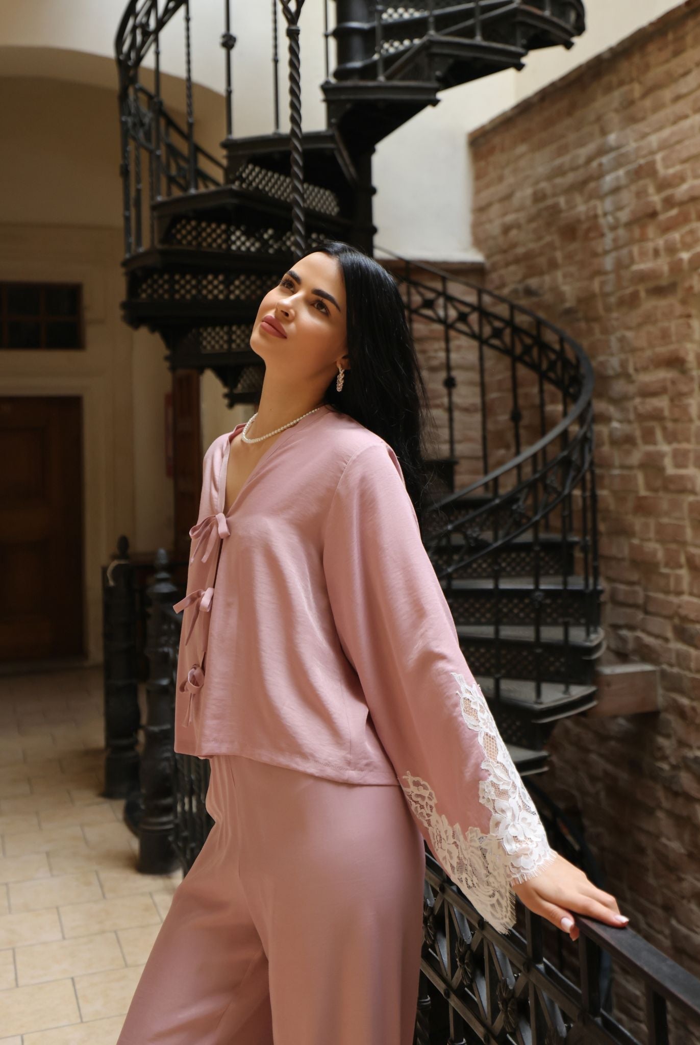 A mid-length shot of a woman leaning against a railing, highlighting the soft and fluid drape of the viscose fabric.