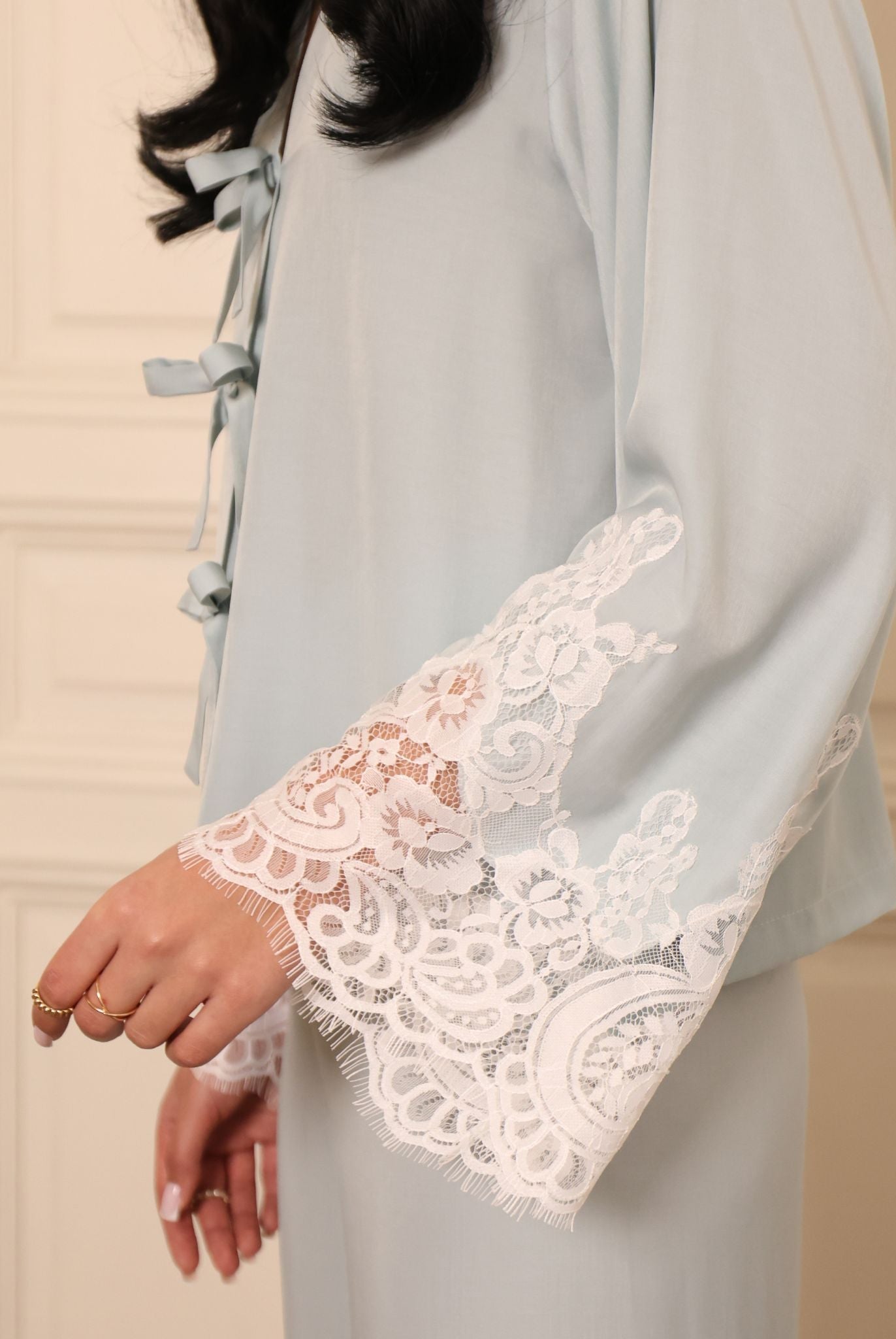 Detailed shot of the sleeve, highlighting the subtle lace accents that add a light, feminine contrast to the look.