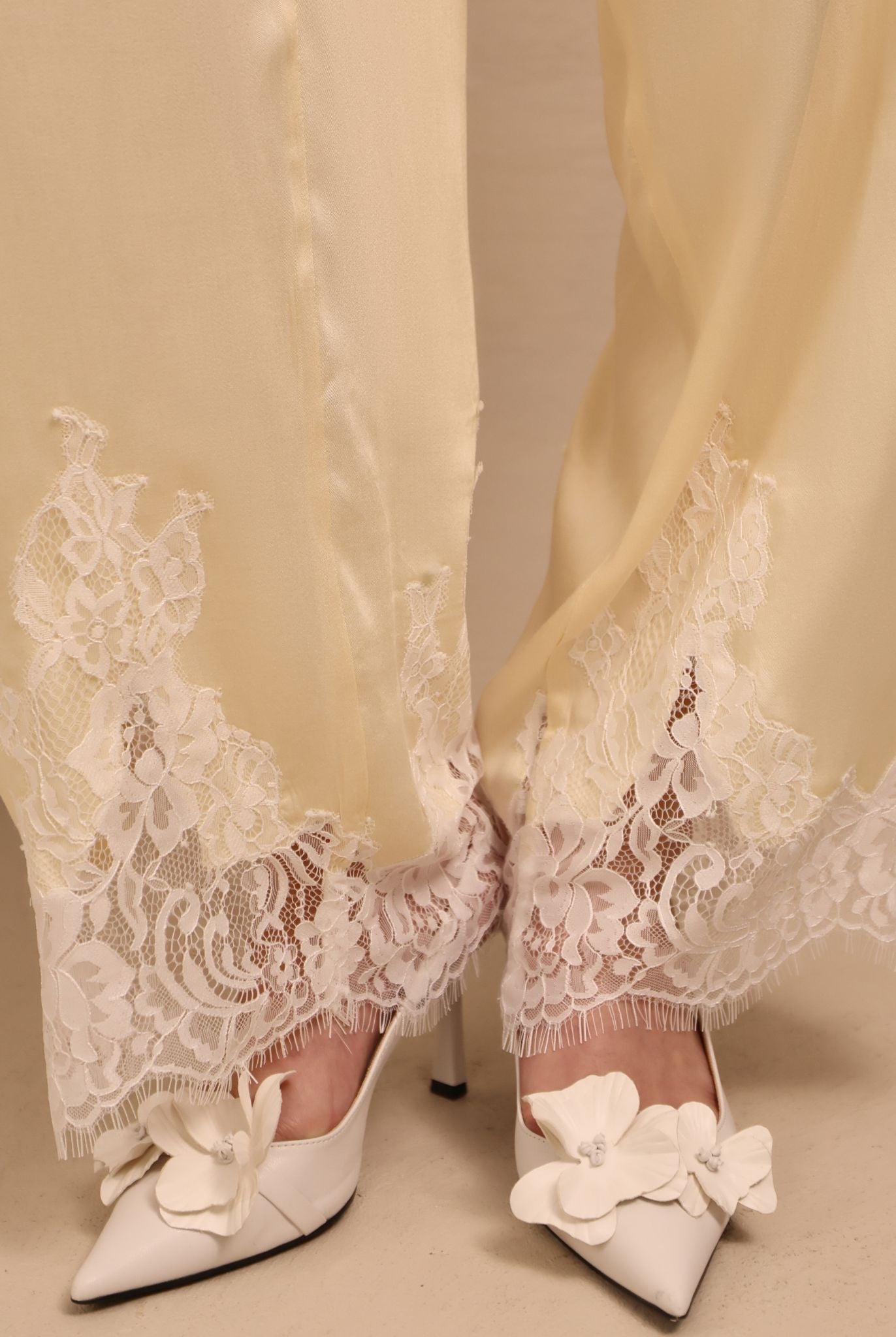 A detailed close-up of the trousers' hem, focusing on the lace accents that soften the silhouette without excess.