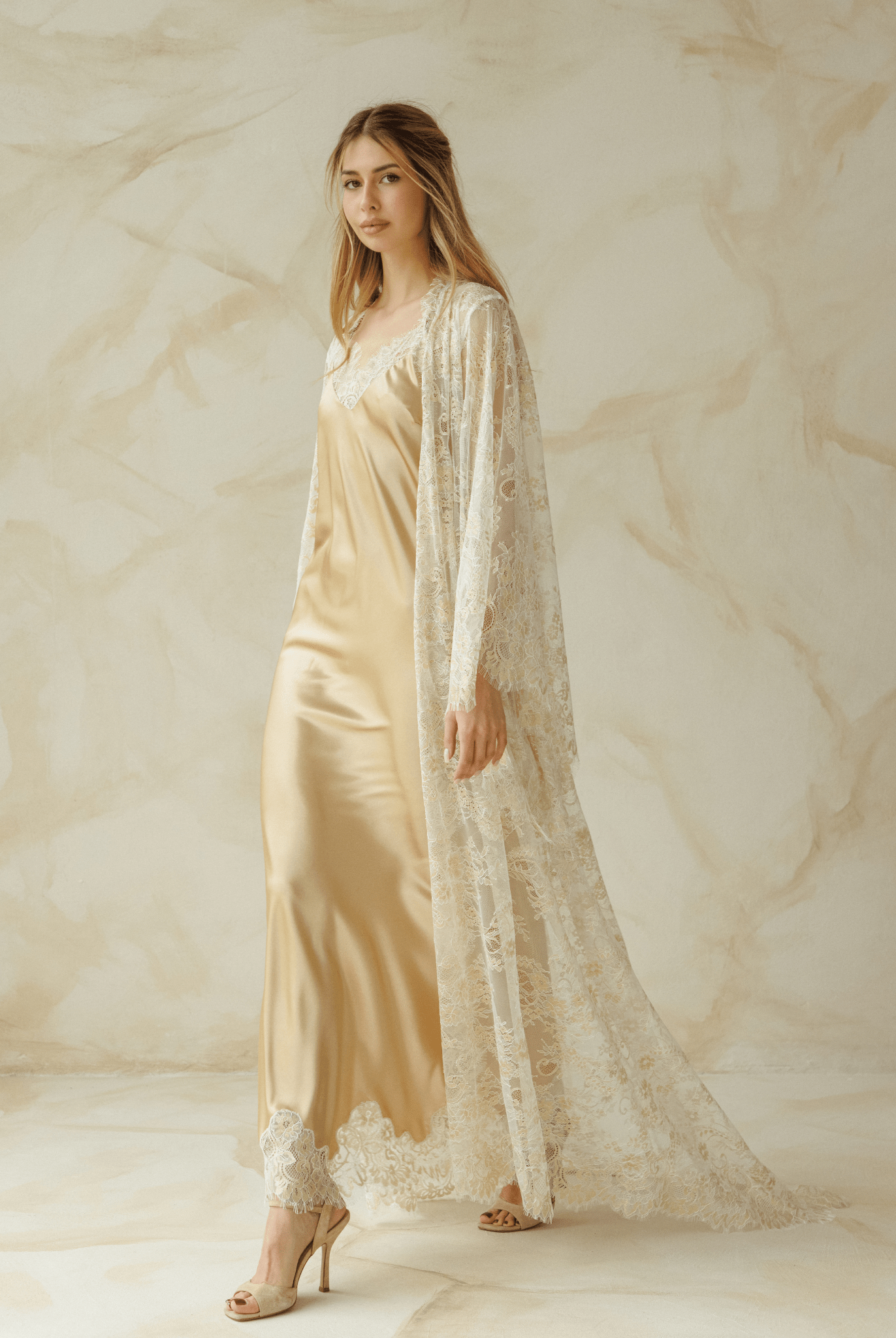 Woman wearing a beige satin nightgown with lace robe draped over shoulders