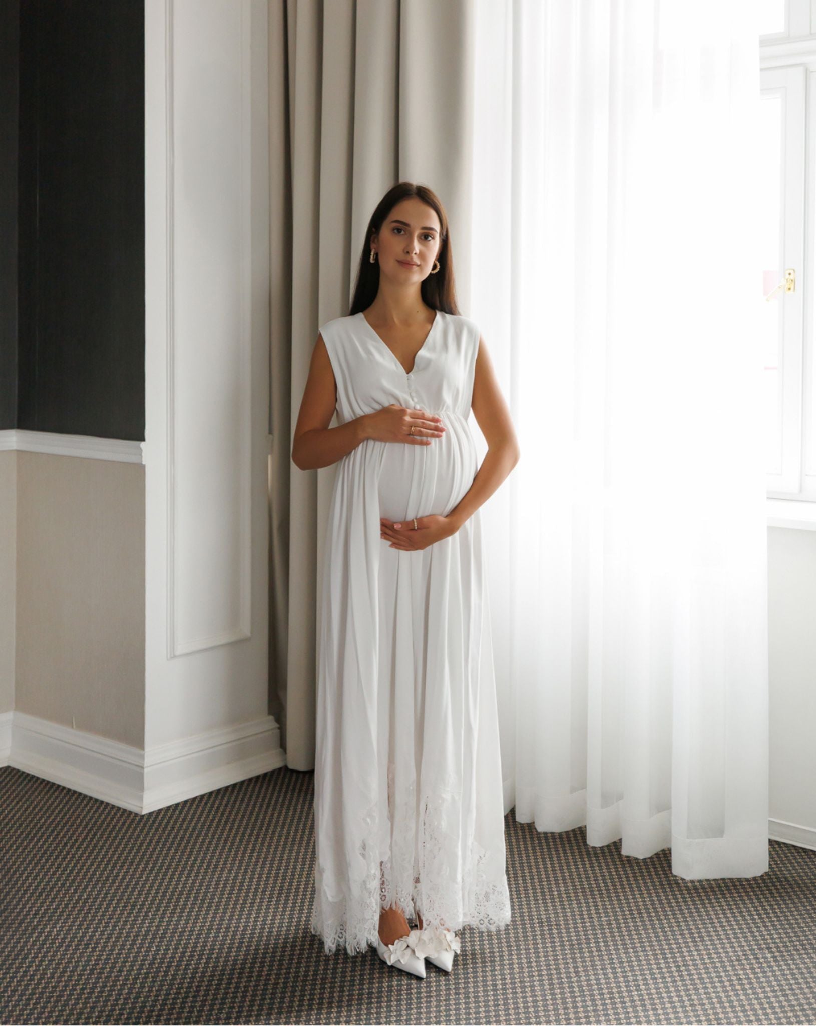 Standing in a maternity nightdress while holding the belly, featuring hidden openings for easy and quick nursing access.