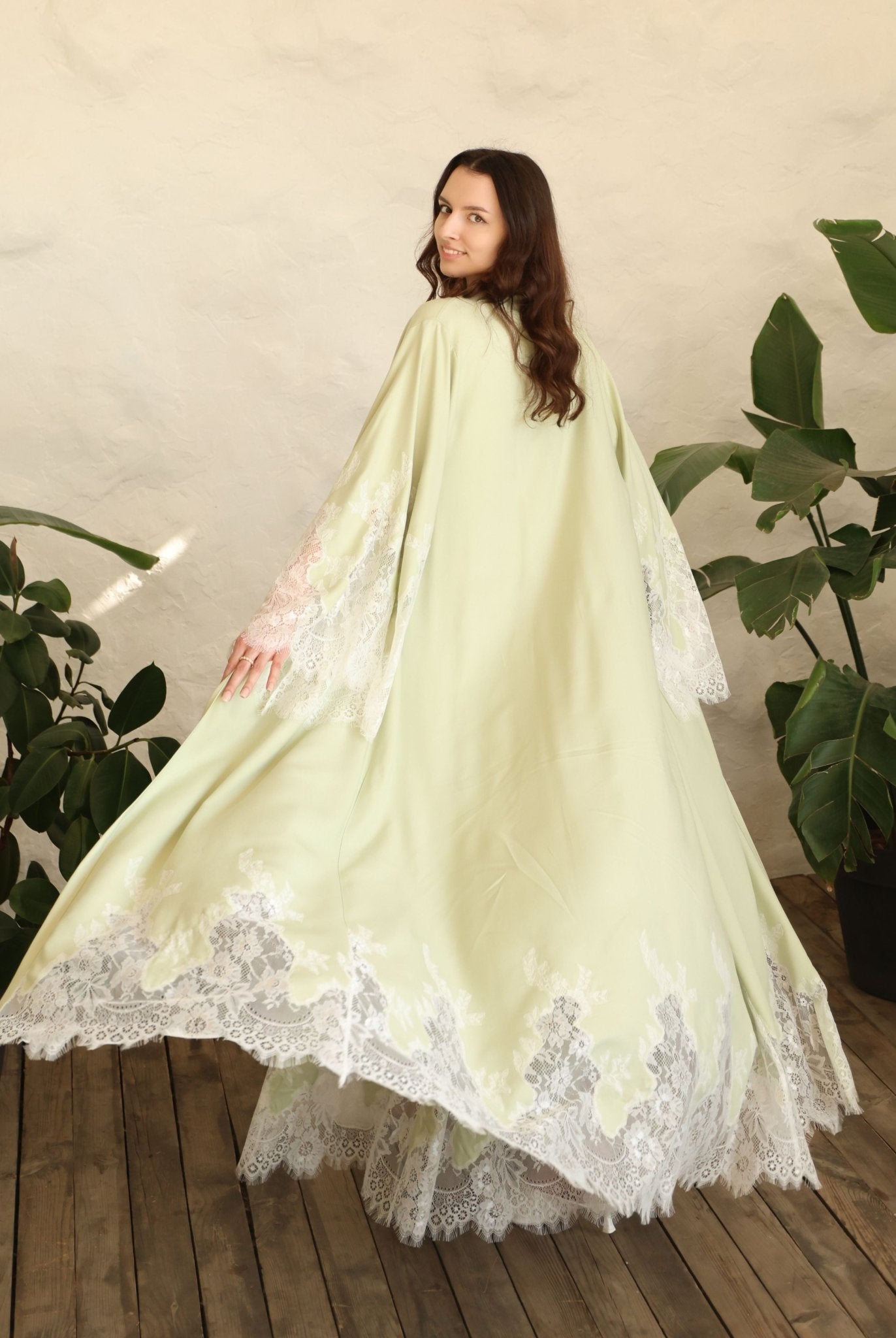 Rear view of the long robe in motion, highlighting the graceful flow and the wide sleeves with lace accents.