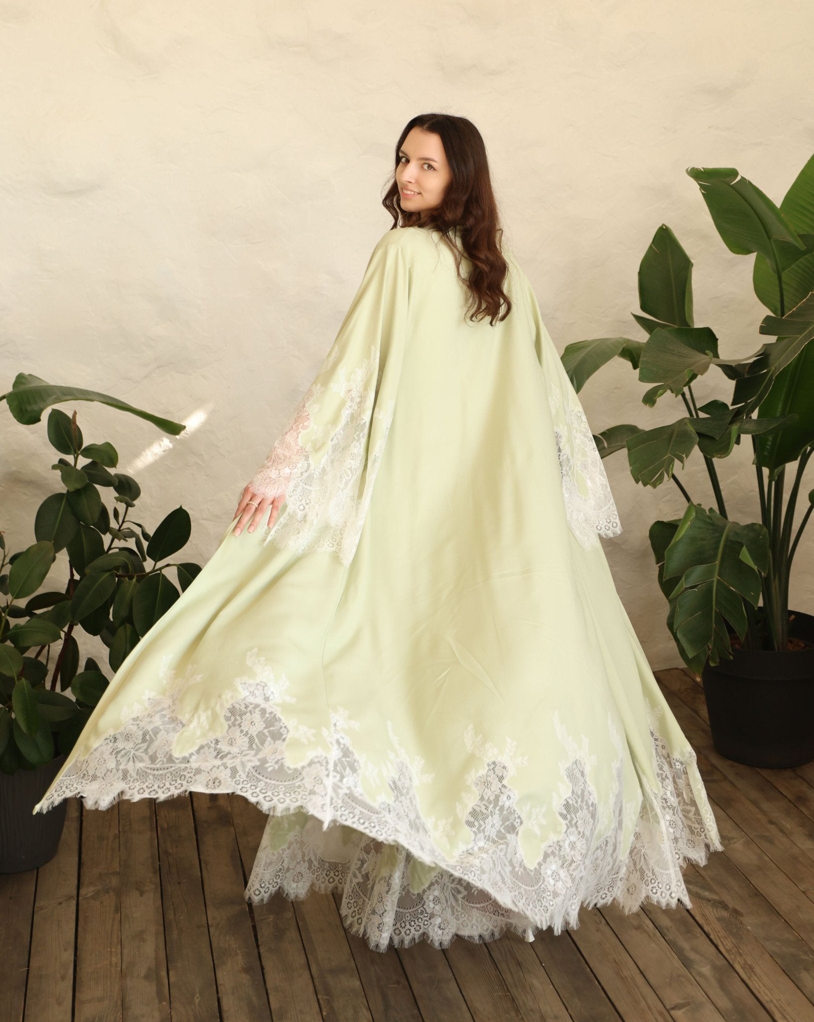 Rear view of the long robe in motion, highlighting the graceful flow and the wide sleeves with lace accents.