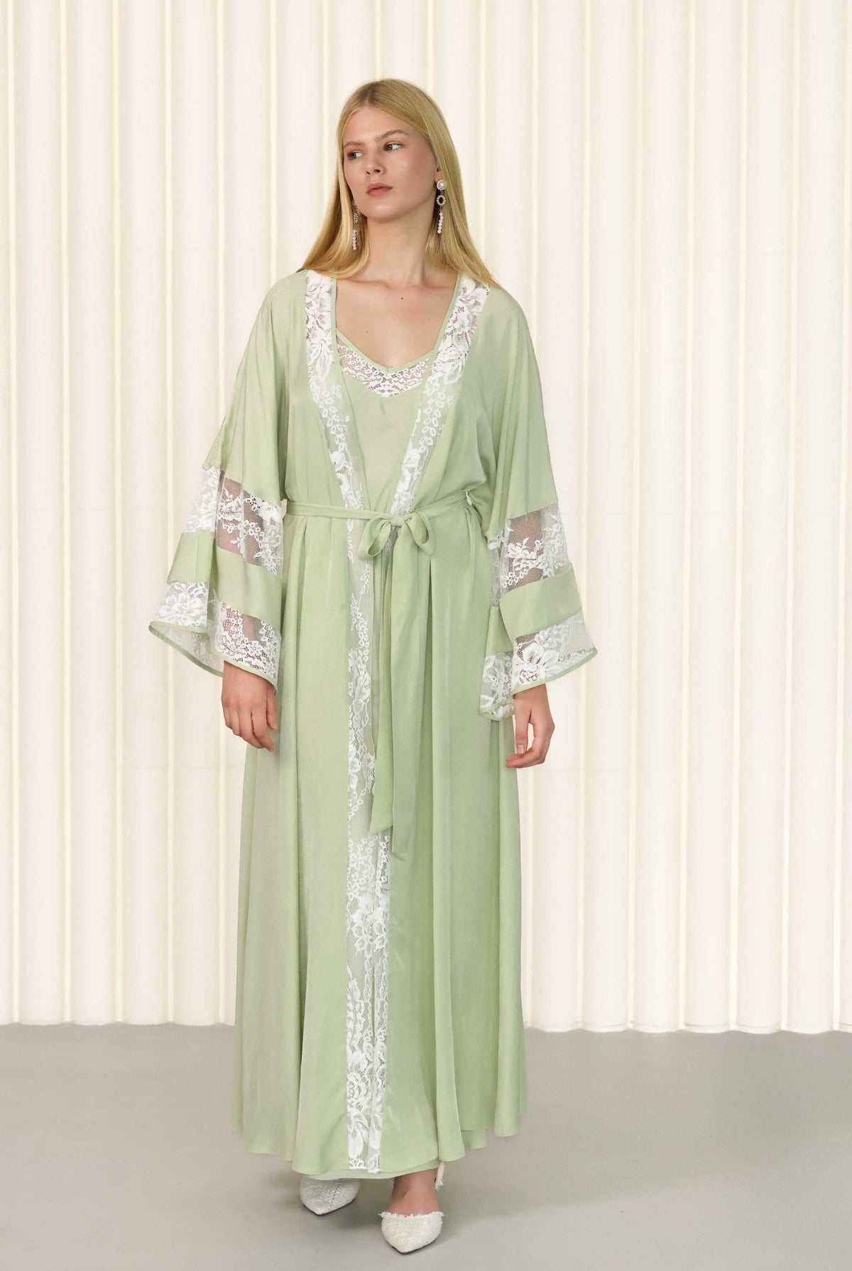 Model in green robe with floral lace sleeve details and gentle motion