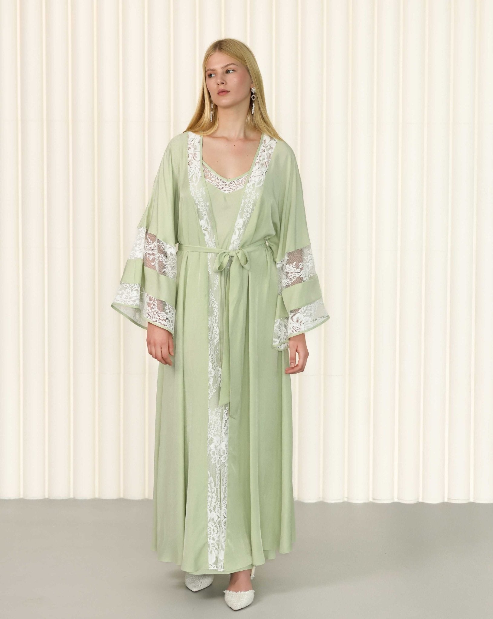 Model in green robe with floral lace sleeve details and gentle motion