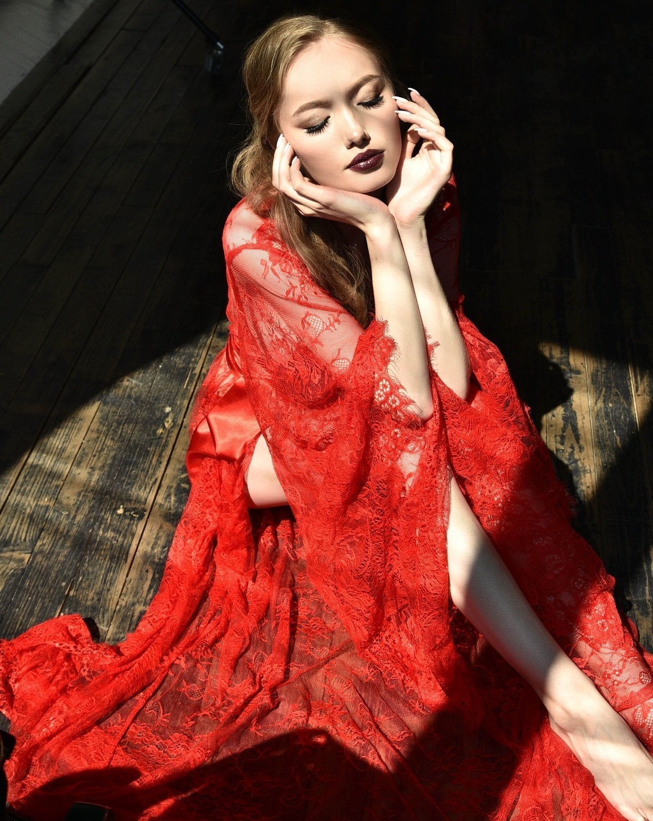 Woman reclining in red lace robe under sunlight
