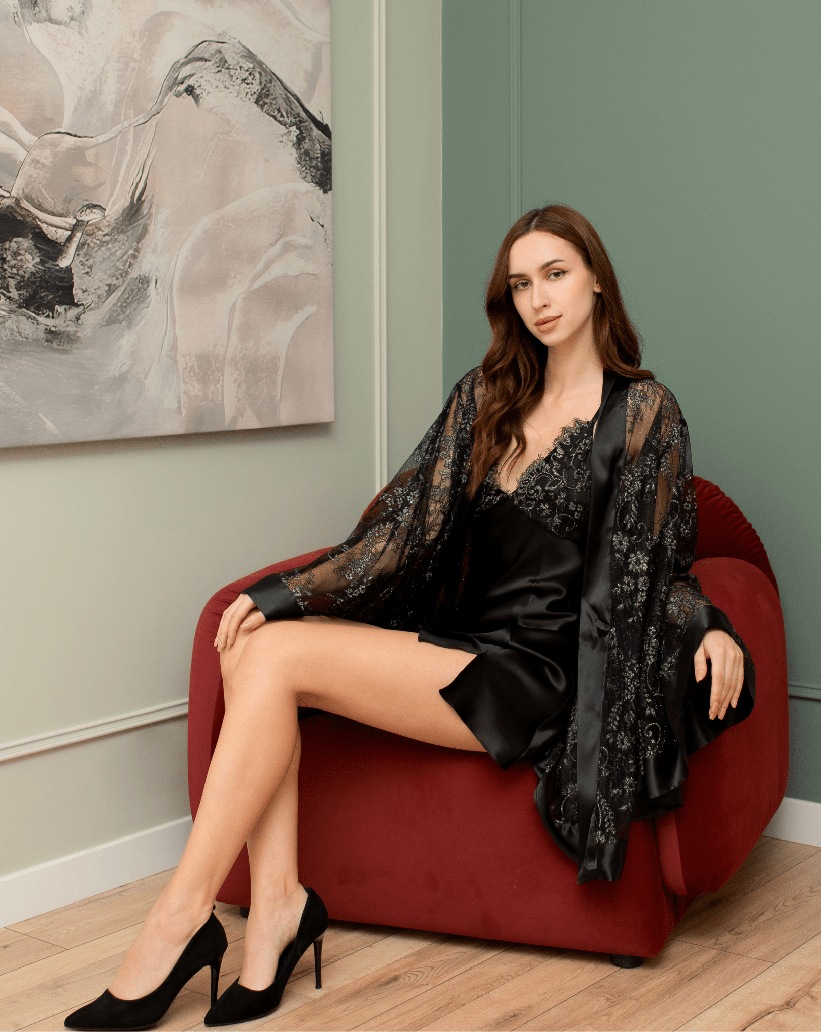Black lace robe worn open, paired with a black slip on a red chair.
