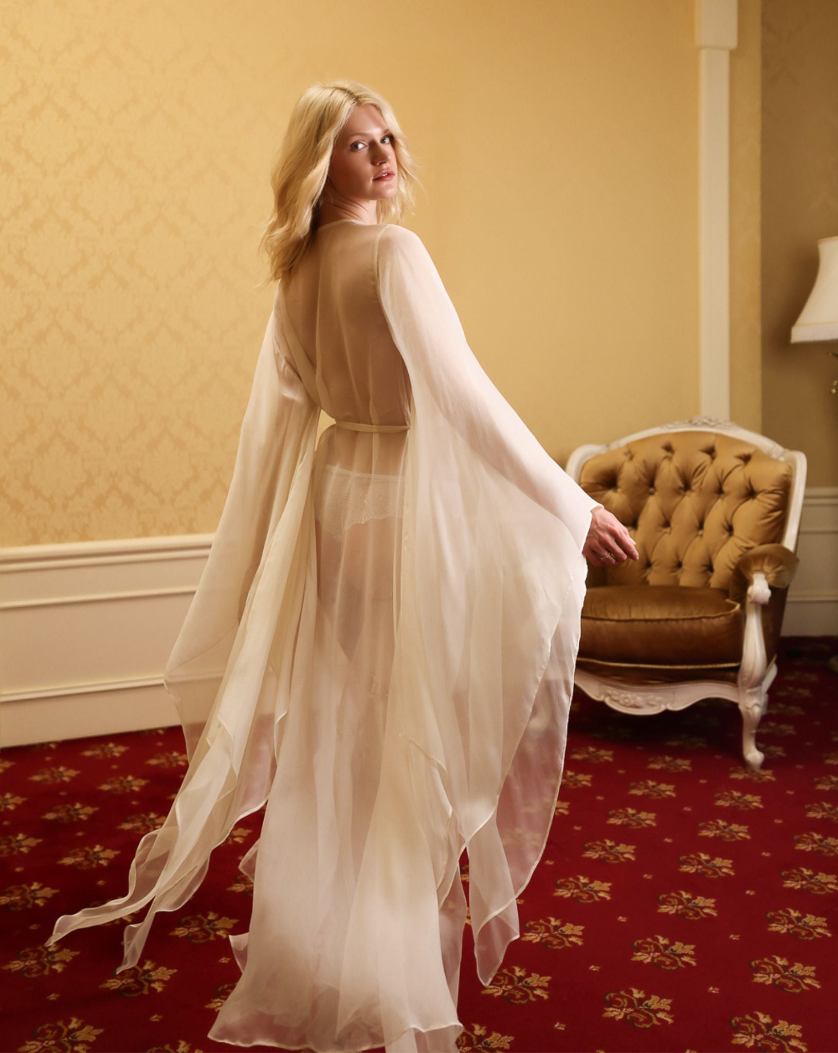 Rear view showing the poetic movement of wide sleeves and sheer hem, creating a beautiful play of light on silk.