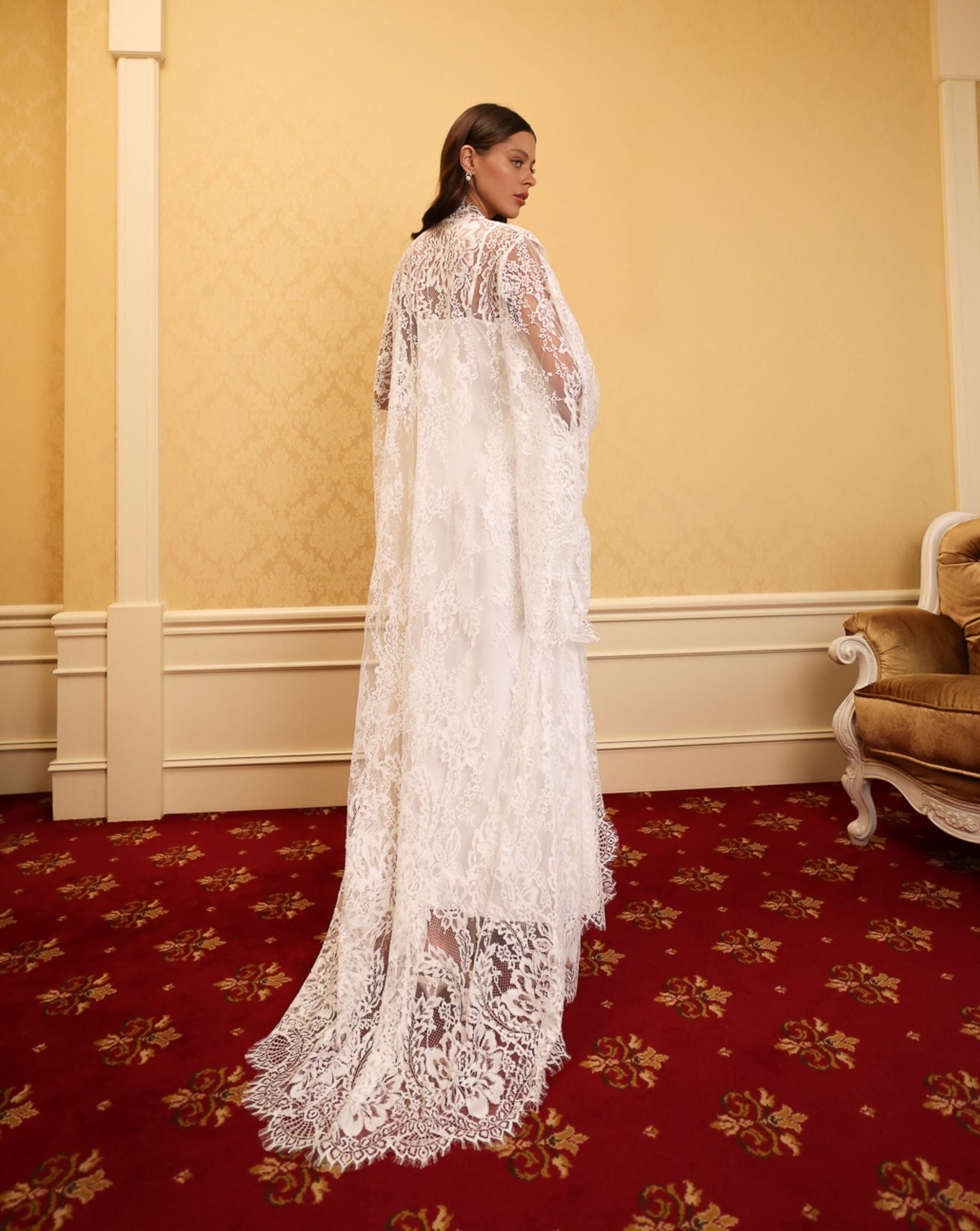 Model wearing a long white lace robe from kafemme on a red carpet background