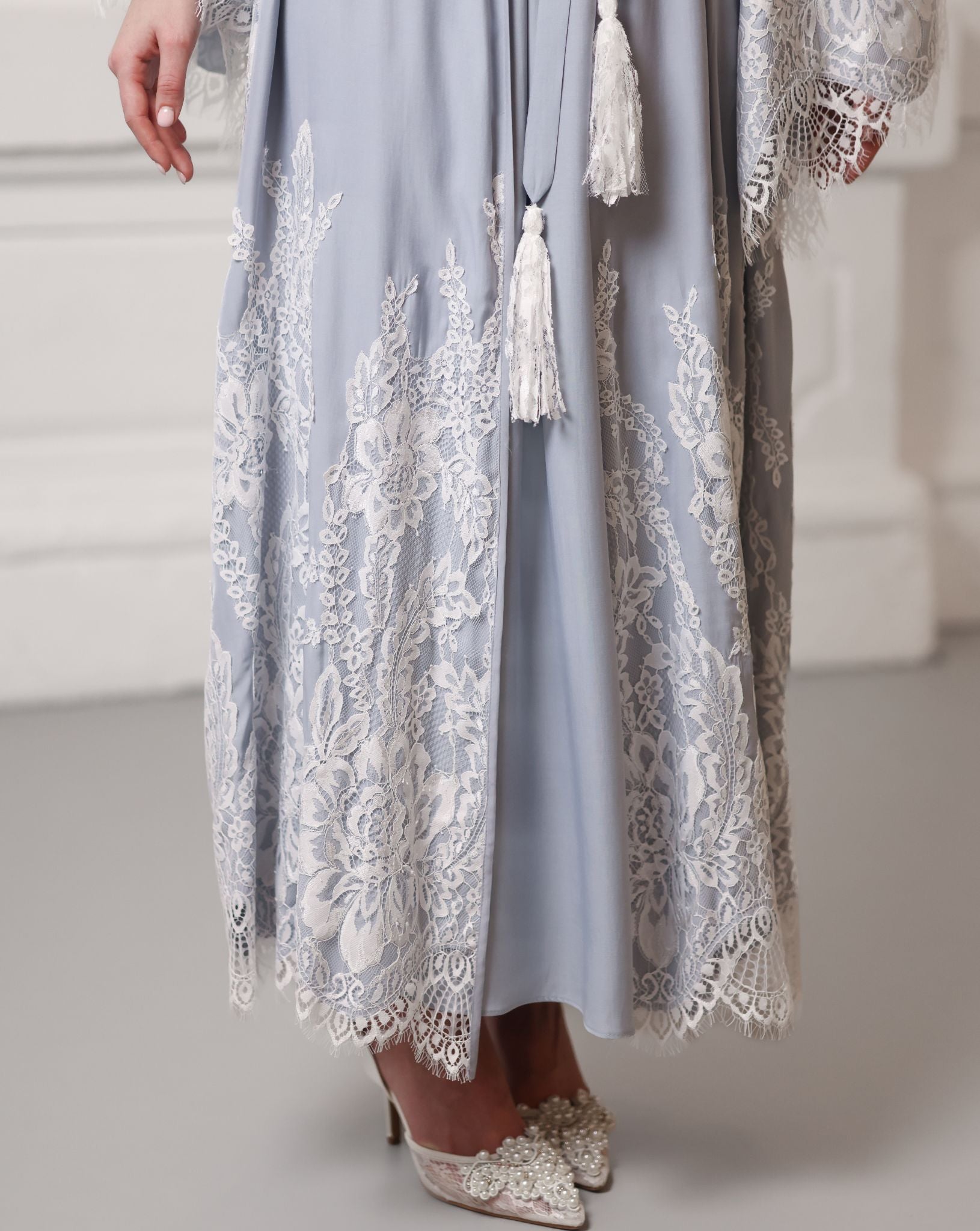 Detail of the robe's hem featuring soft French lace and decorative tassels for a touch of style.