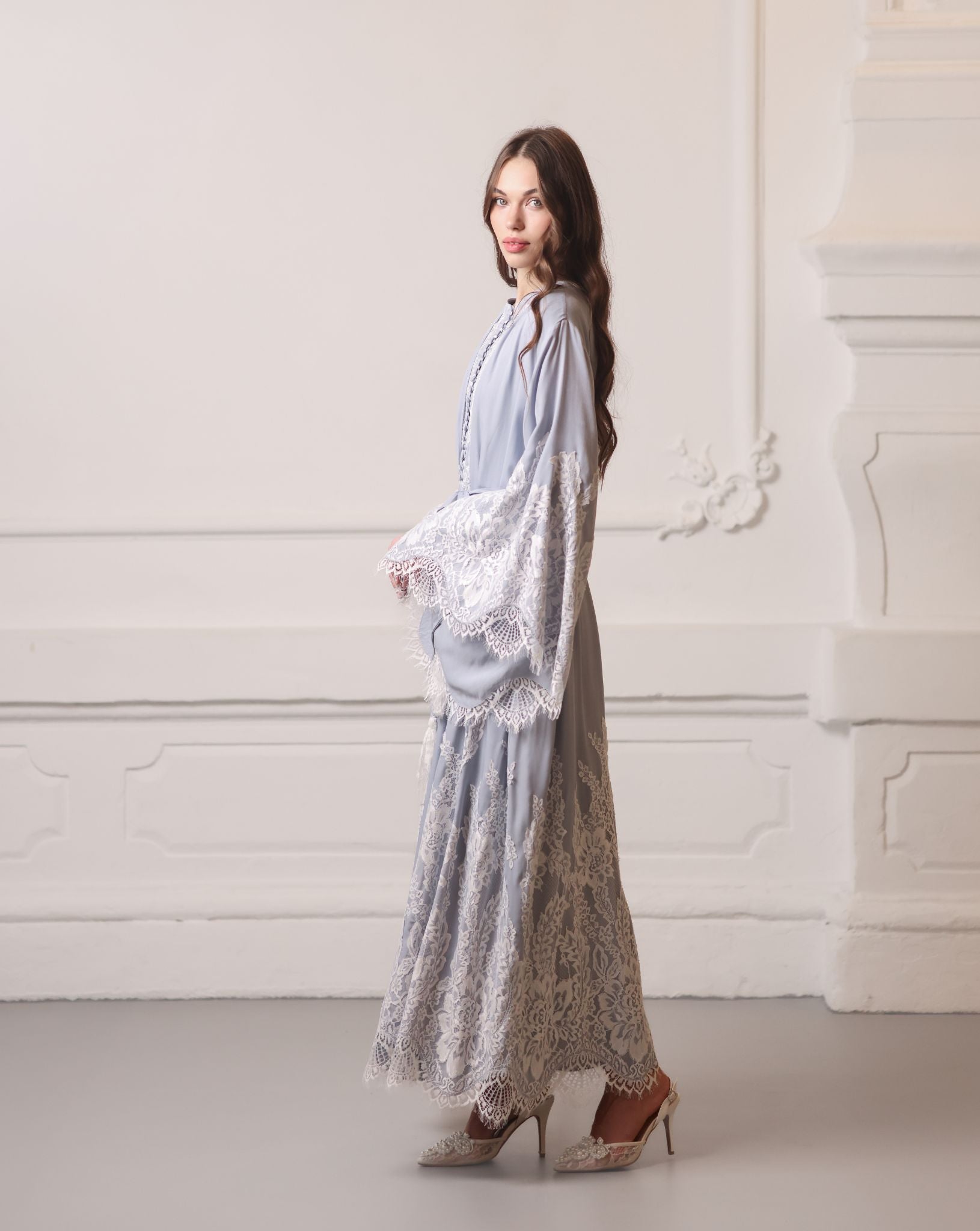 Side profile in a lace robe, showcasing the floor-length drape and elegant floral patterns.