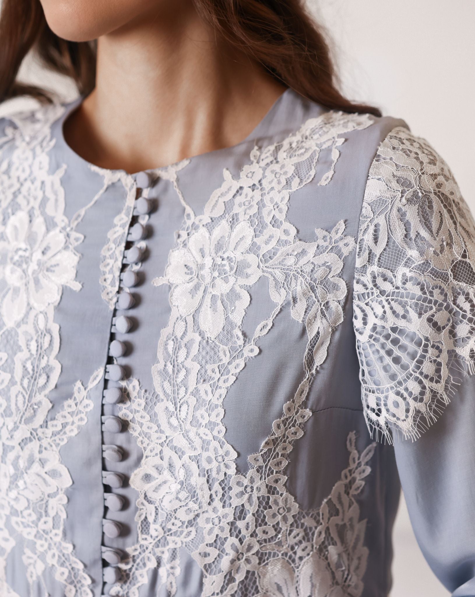Close-up of fabric-covered buttons and French lace on a nightdress, perfect for breastfeeding access.